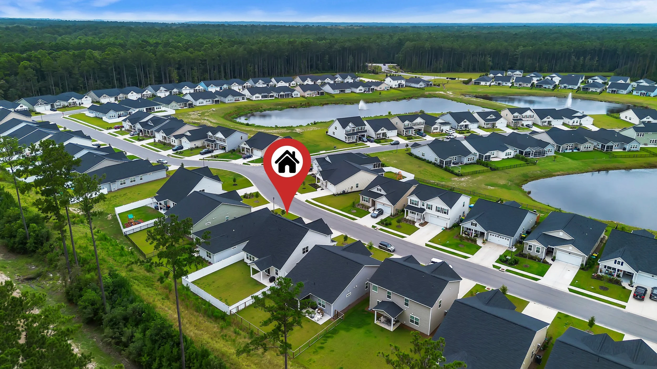 Aerial view of a suburban neighborhood with single-family homes, ponds, and green lawns.