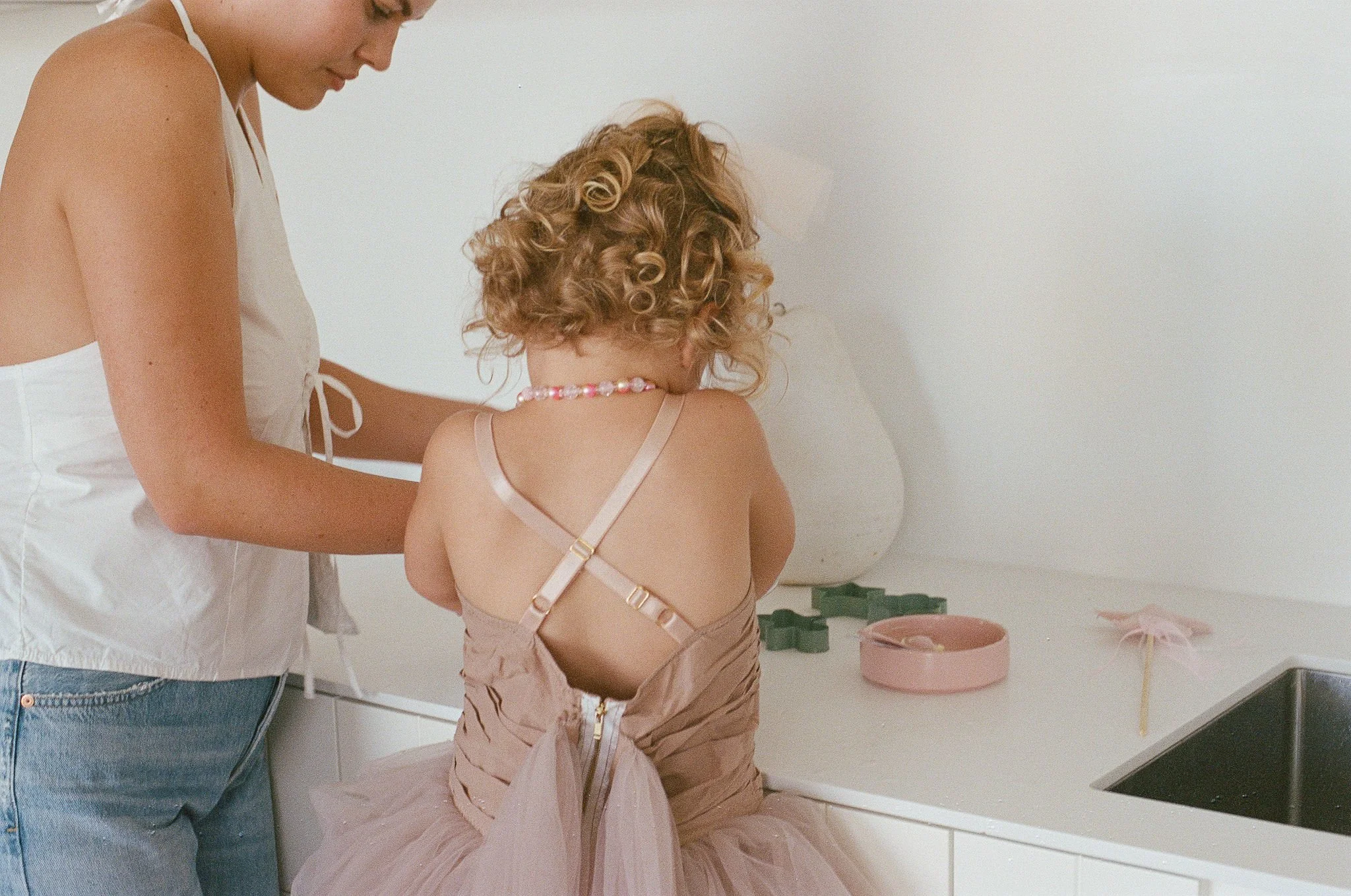 A babysitter helping girl with curly hair bake cookies