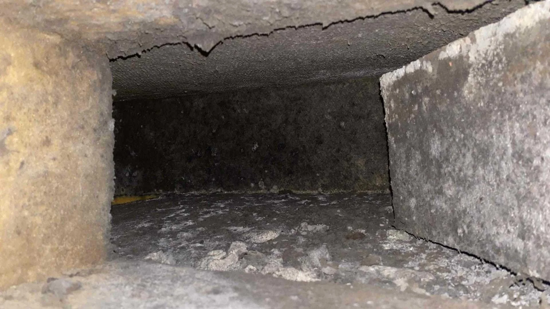 A close-up view inside a brick chimney or flue showing the interior brick lining and some debris at the bottom.