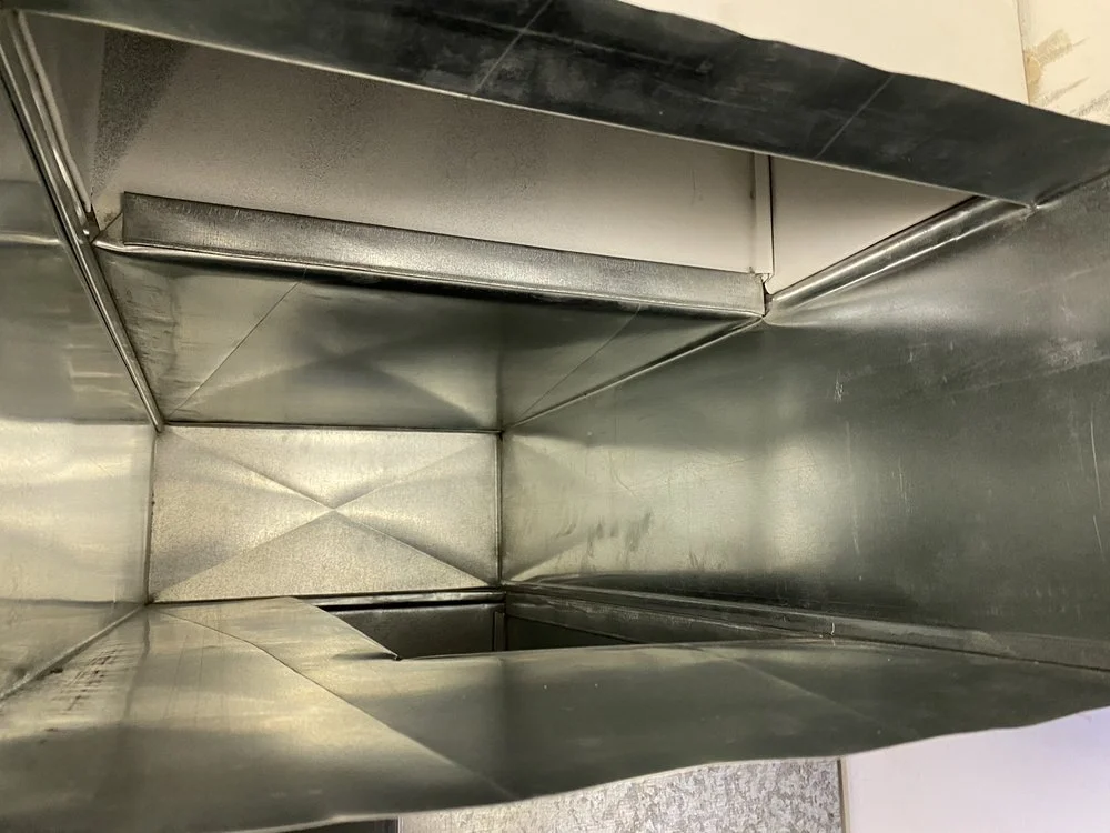 Interior view of a metallic, rectangular duct or vent with reflective surfaces, likely part of an HVAC system.