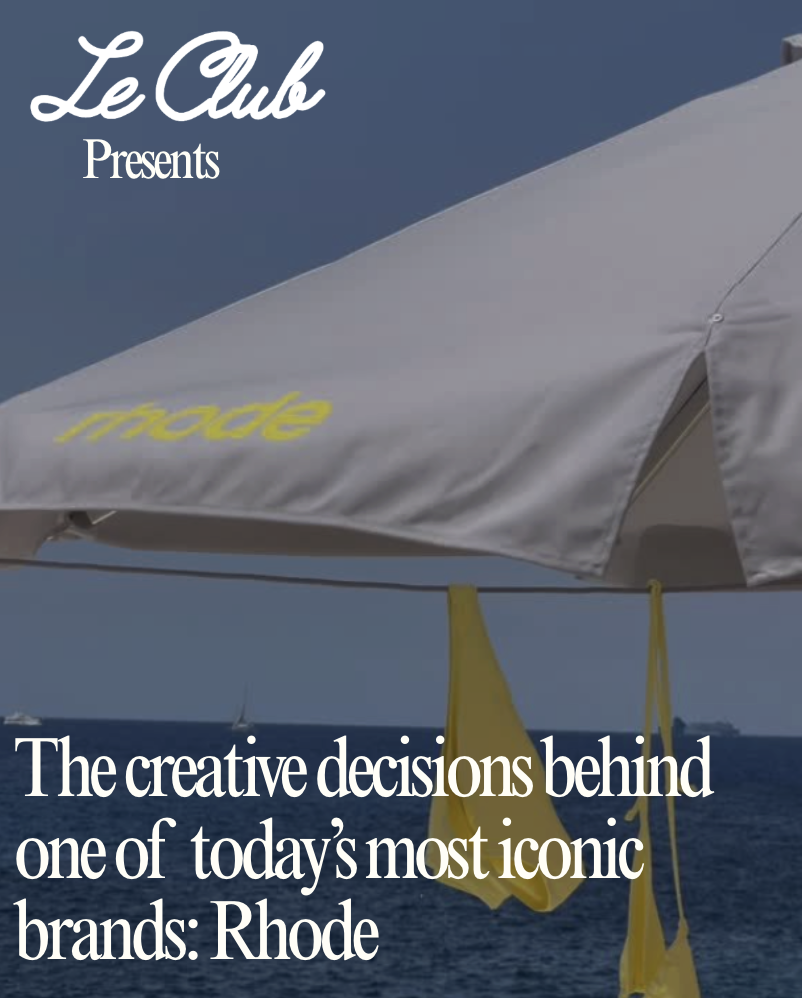 A beach scene featuring a large white beach umbrella with yellow towels hanging from it and a view of the ocean in the background.