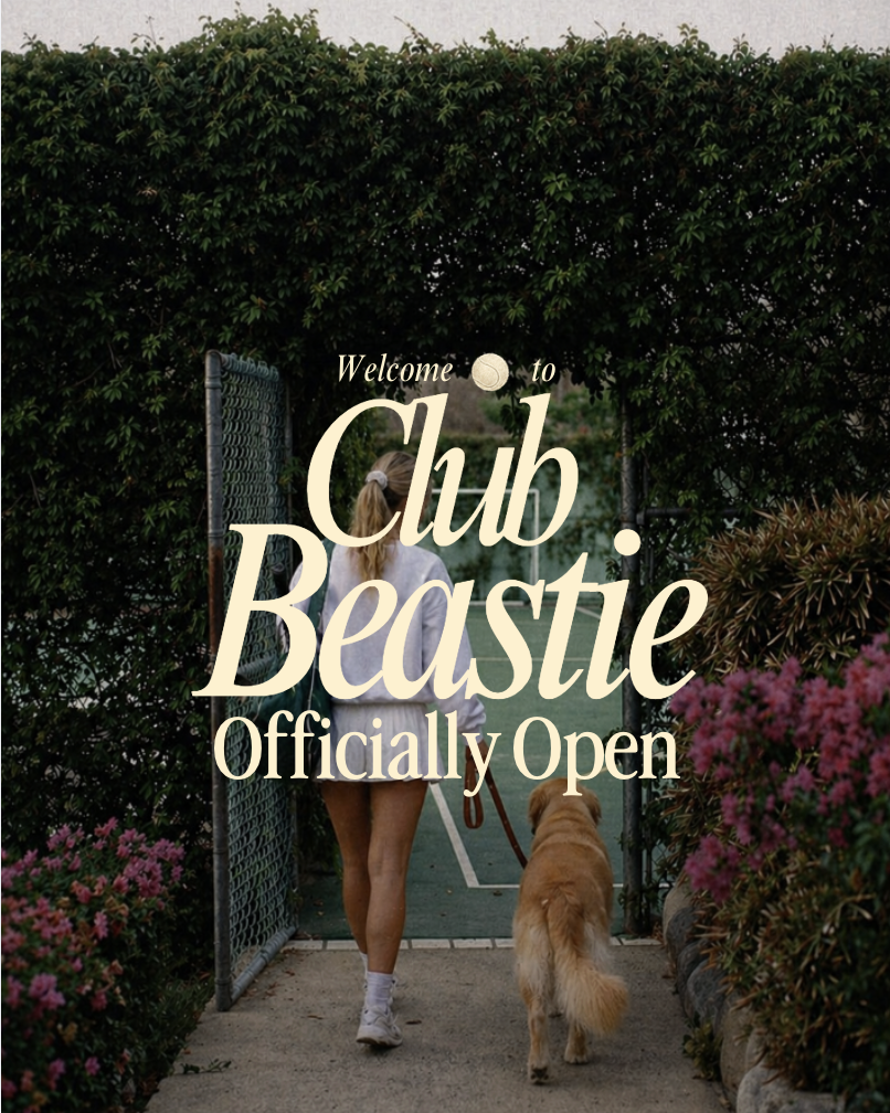 A person walking a dog through an open gate at the entrance of a club, with greenery and flowers around.
