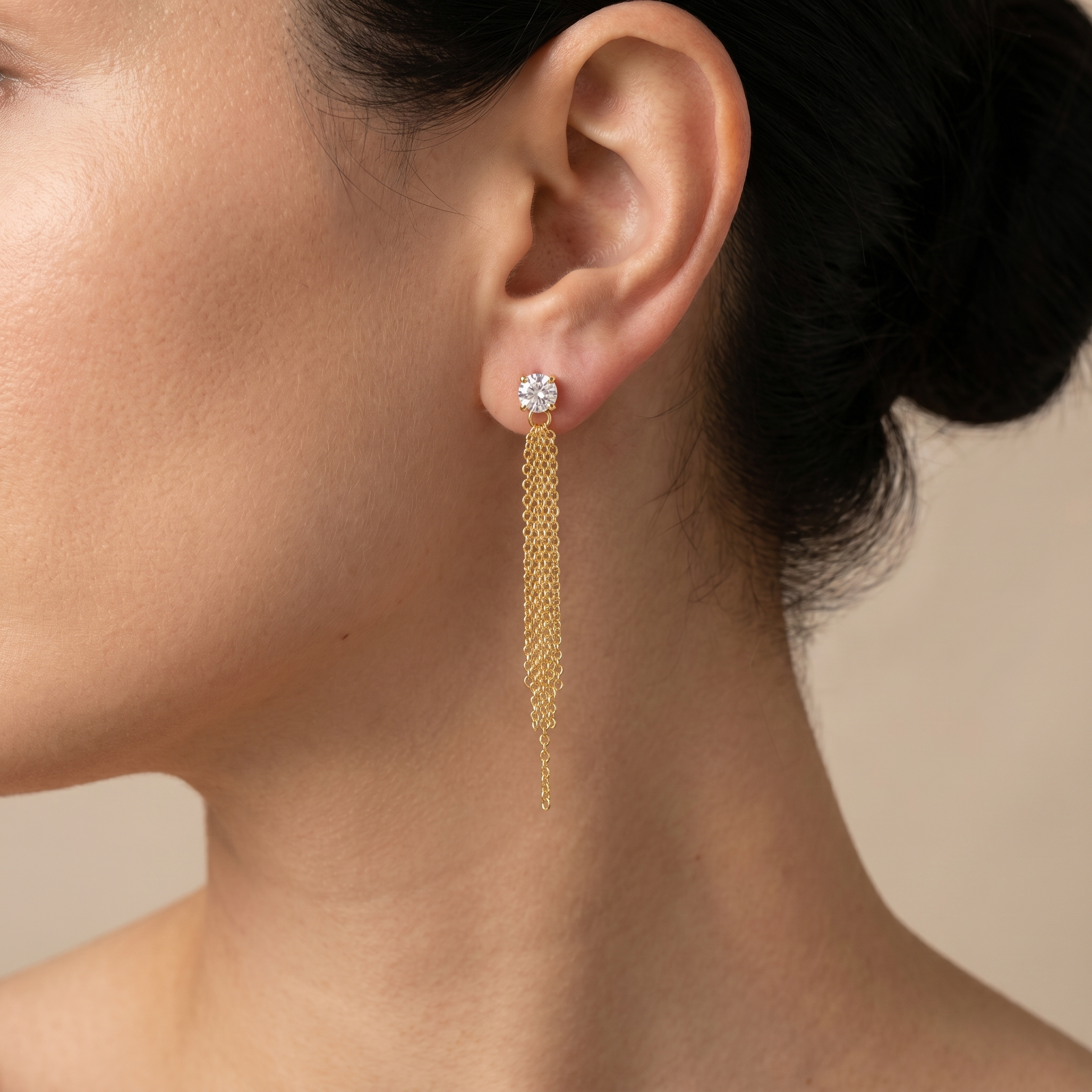Close-up of 18K gold plated 925 sterling silver tassel earrings with zirconia stones, worn on the ear to show size and elegant chain movement.