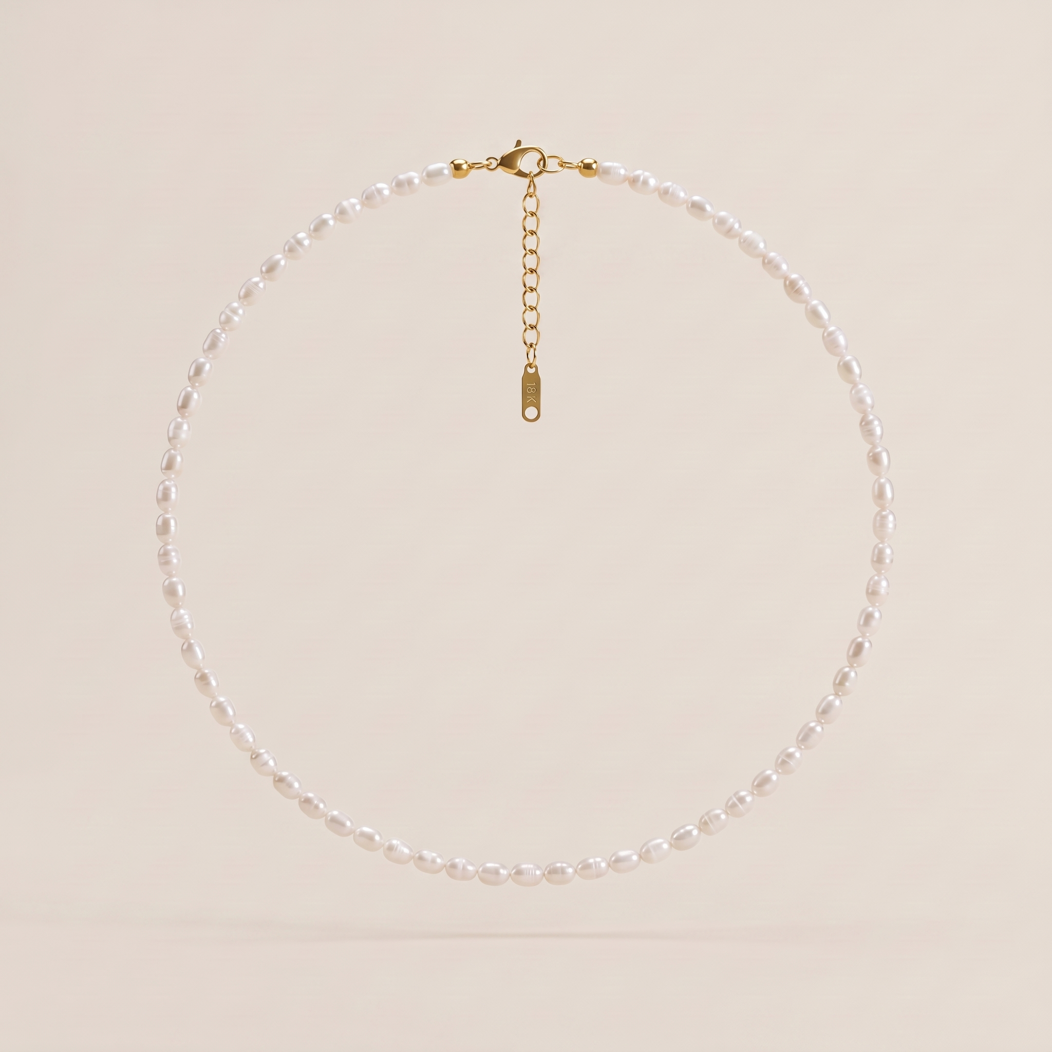 LAURRÈ white freshwater rice pearl choker necklace with delicate 4–5 mm natural pearls, 18K gold-plated clasp and adjustable chain on an ivory background.