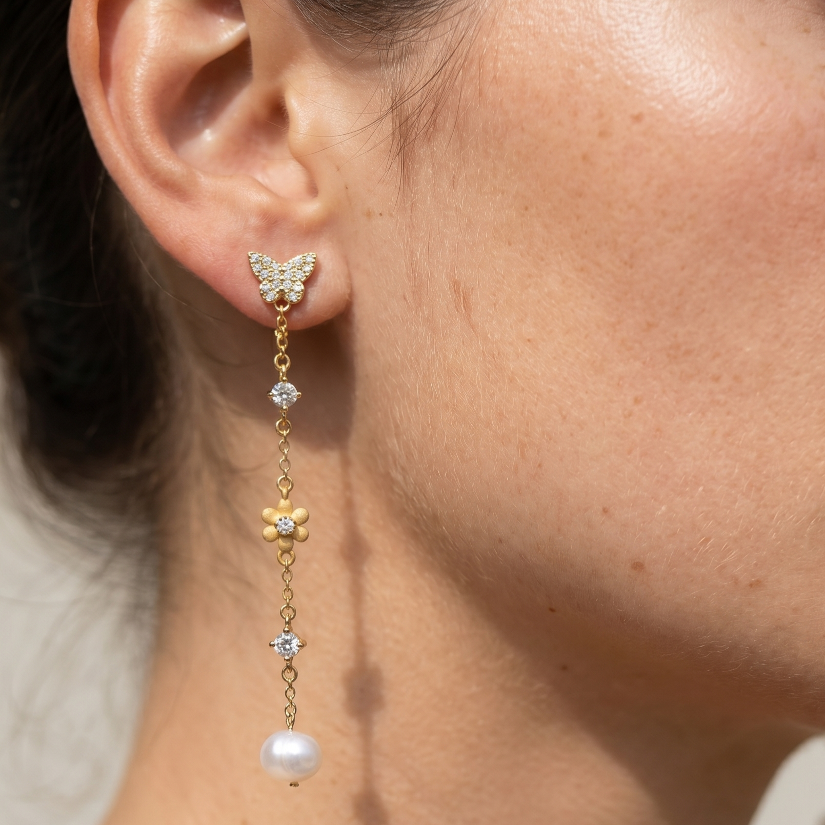 Woman wearing 18K gold plated sterling silver butterfly pearl drop earrings with cubic zirconia and freshwater pearls