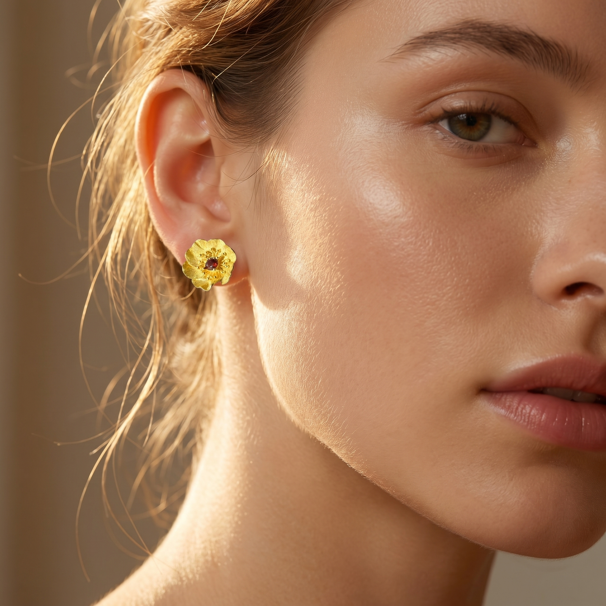 Elegant gold flower earrings with red tourmaline gemstone worn by female model