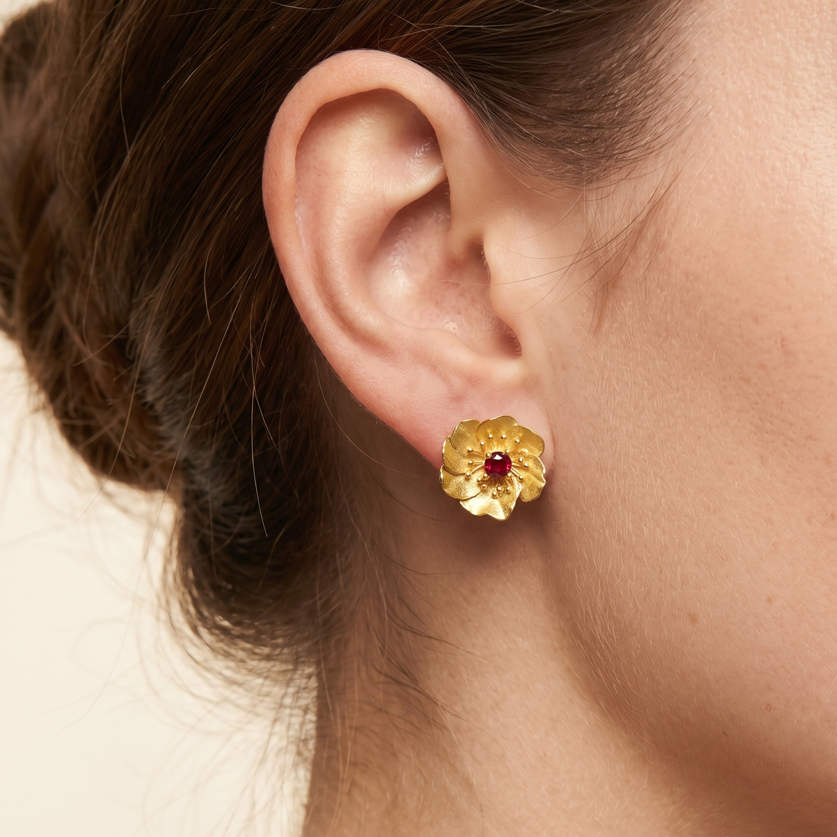 Woman wearing gold plated sterling silver flower stud earrings with natural red tourmaline