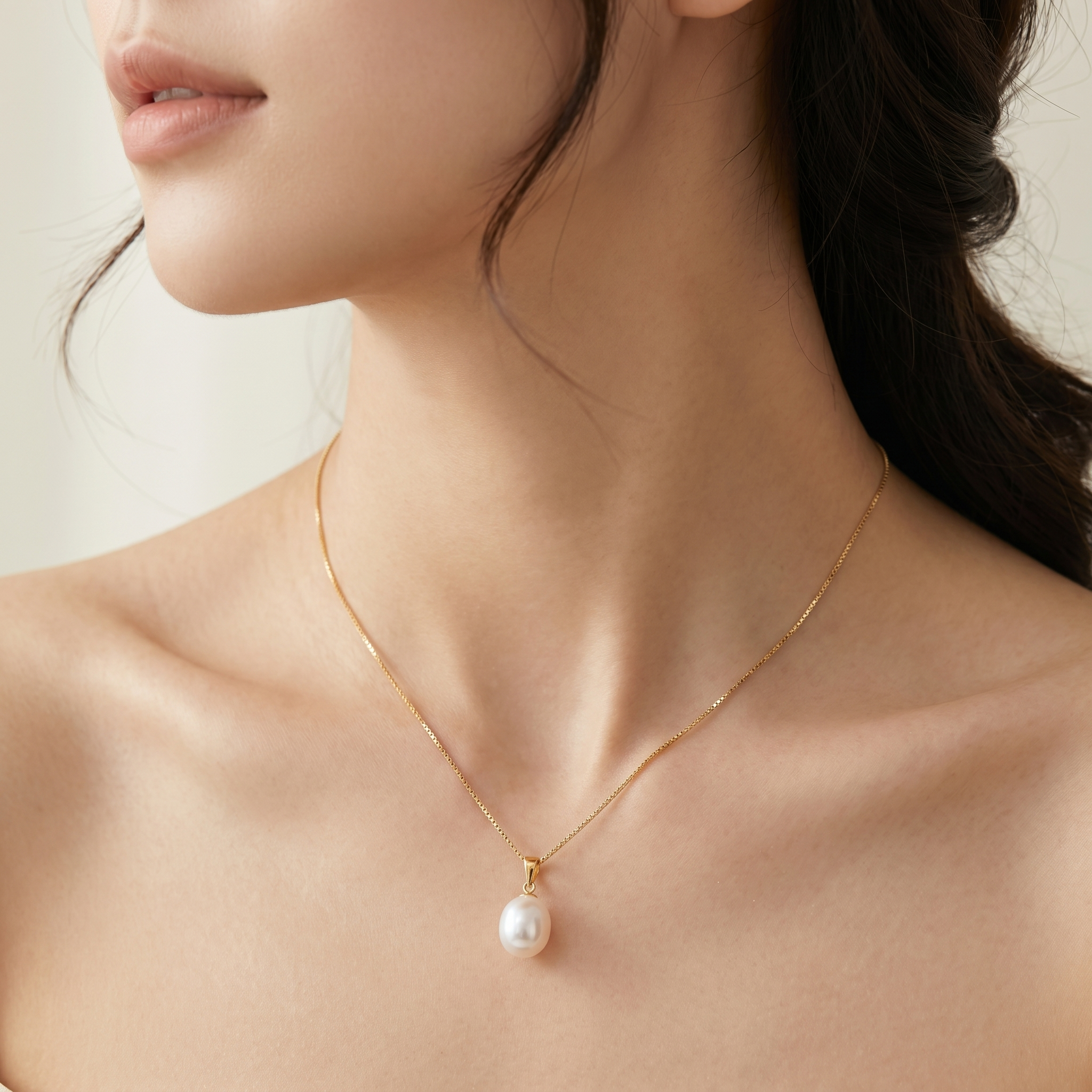Woman wearing freshwater pearl pendant necklace in 18K gold plated sterling silver.