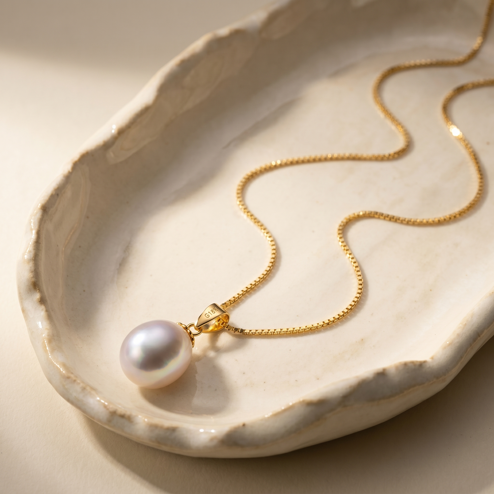 Freshwater pearl pendant necklace in 18K gold plated 925 sterling silver, displayed on a handcrafted ceramic tray with elegant box chain detail.