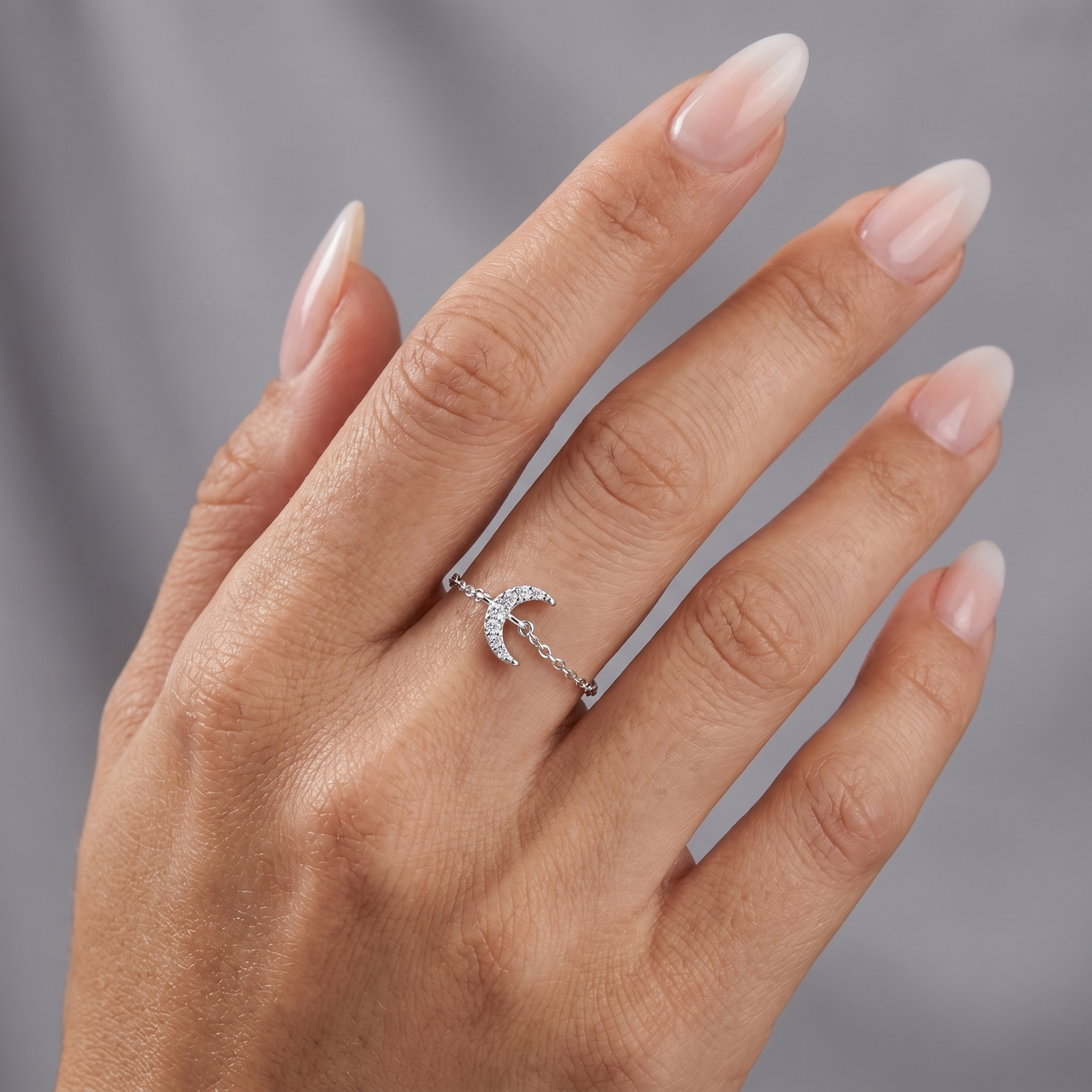 Model wearing a dainty 925 sterling silver crescent moon ring with sparkling zirconia stones and adjustable chain band.