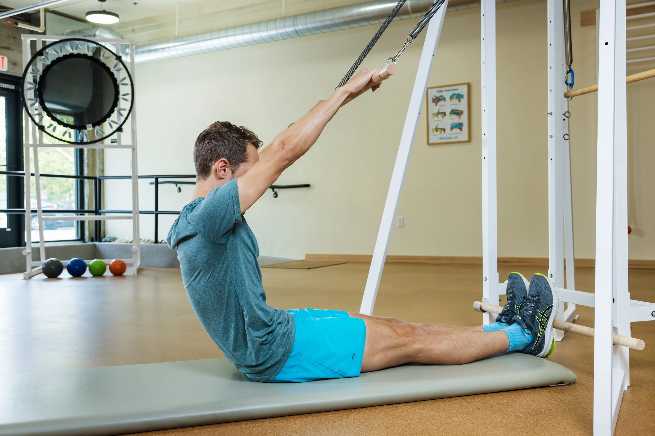 Horizontal photo of a man in athletic attire working out on a unique and innovative piece of exercise equipment in a calm space with white walls and light wood floors at ActiveLab gym in Vancouver, WA