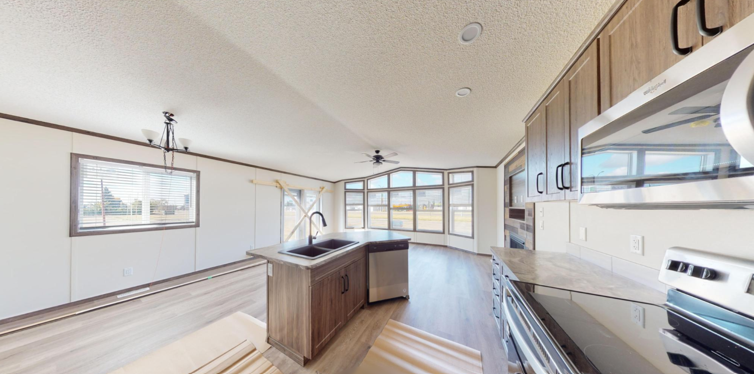Spacious kitchen with wood cabinets, black stove, marble countertop, and large bay windows with a view outside.
