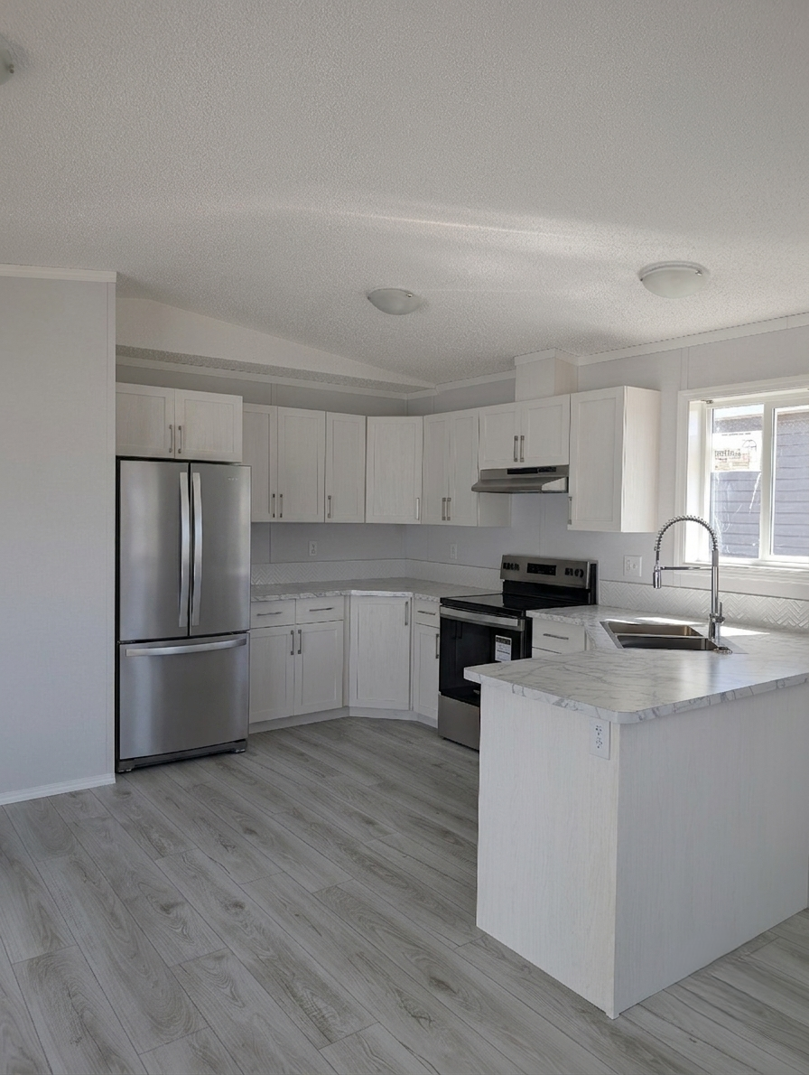 Modern kitchen with white cabinets, stainless steel refrigerator, black stove, marble countertops, and light-colored wooden flooring.