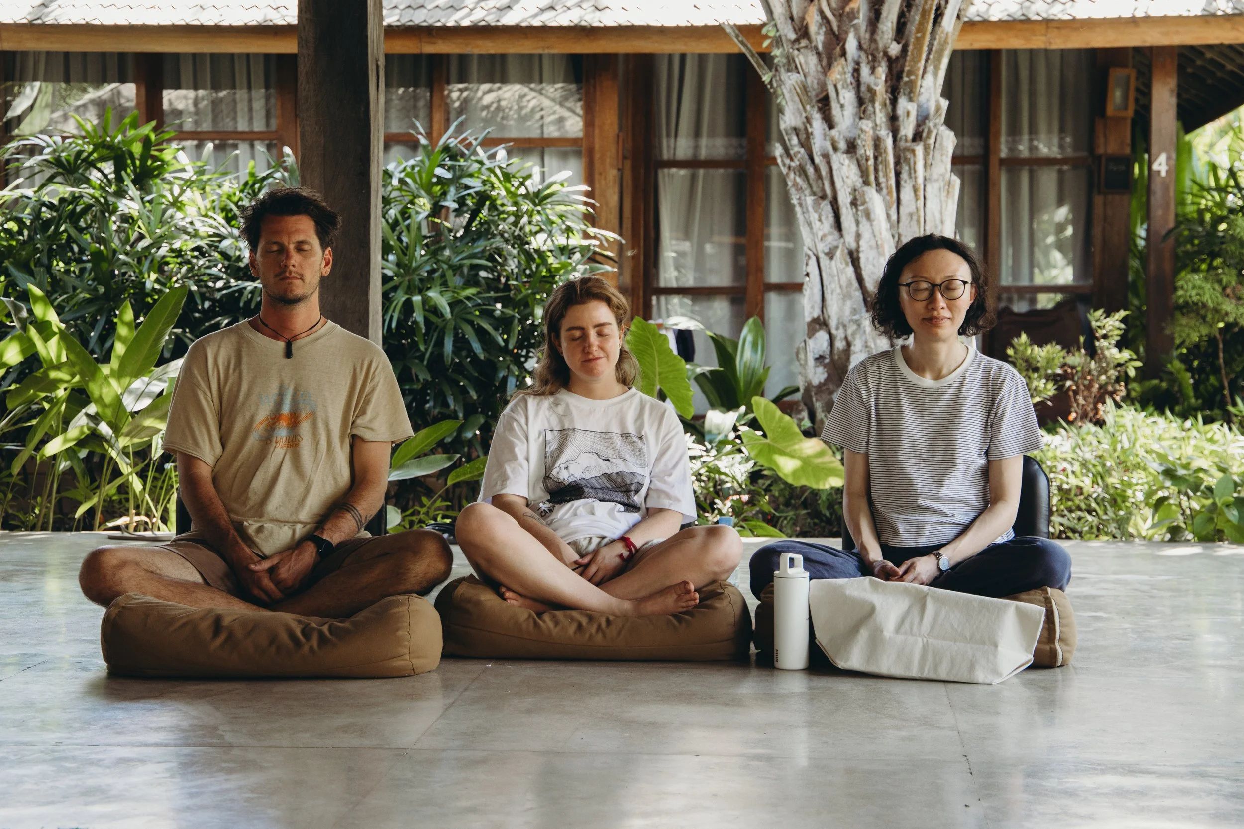 Three people meditating comfortably together, relaxed and at ease.