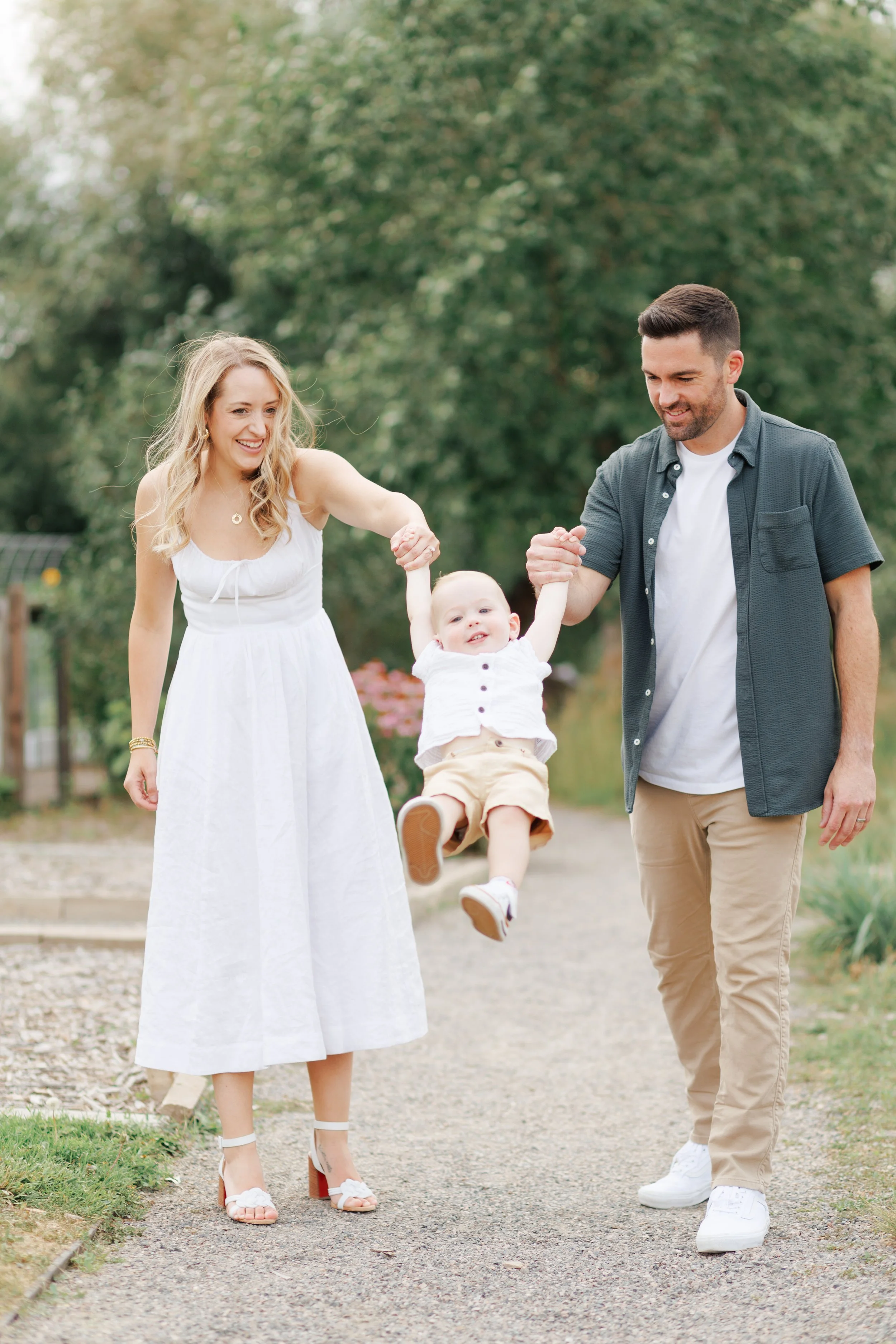 Photo of a happy young family enjoying a walk outdoors, holding and swinging the child.