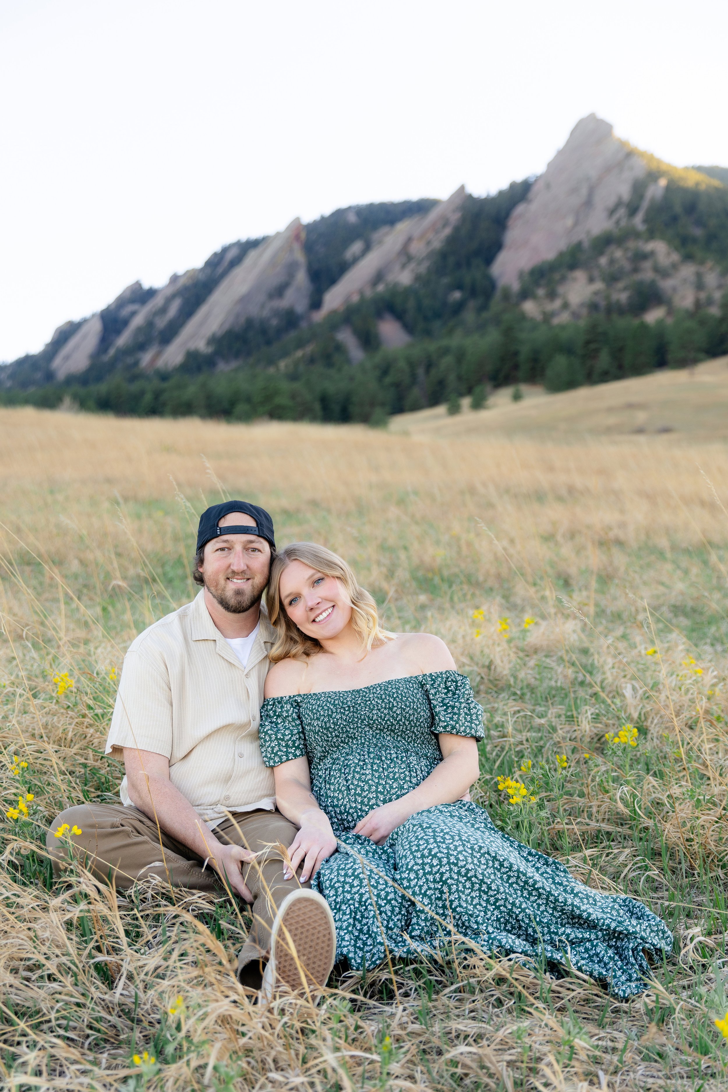 Couple sitting in grass during maternity photo session near Fort Collins, Colorado