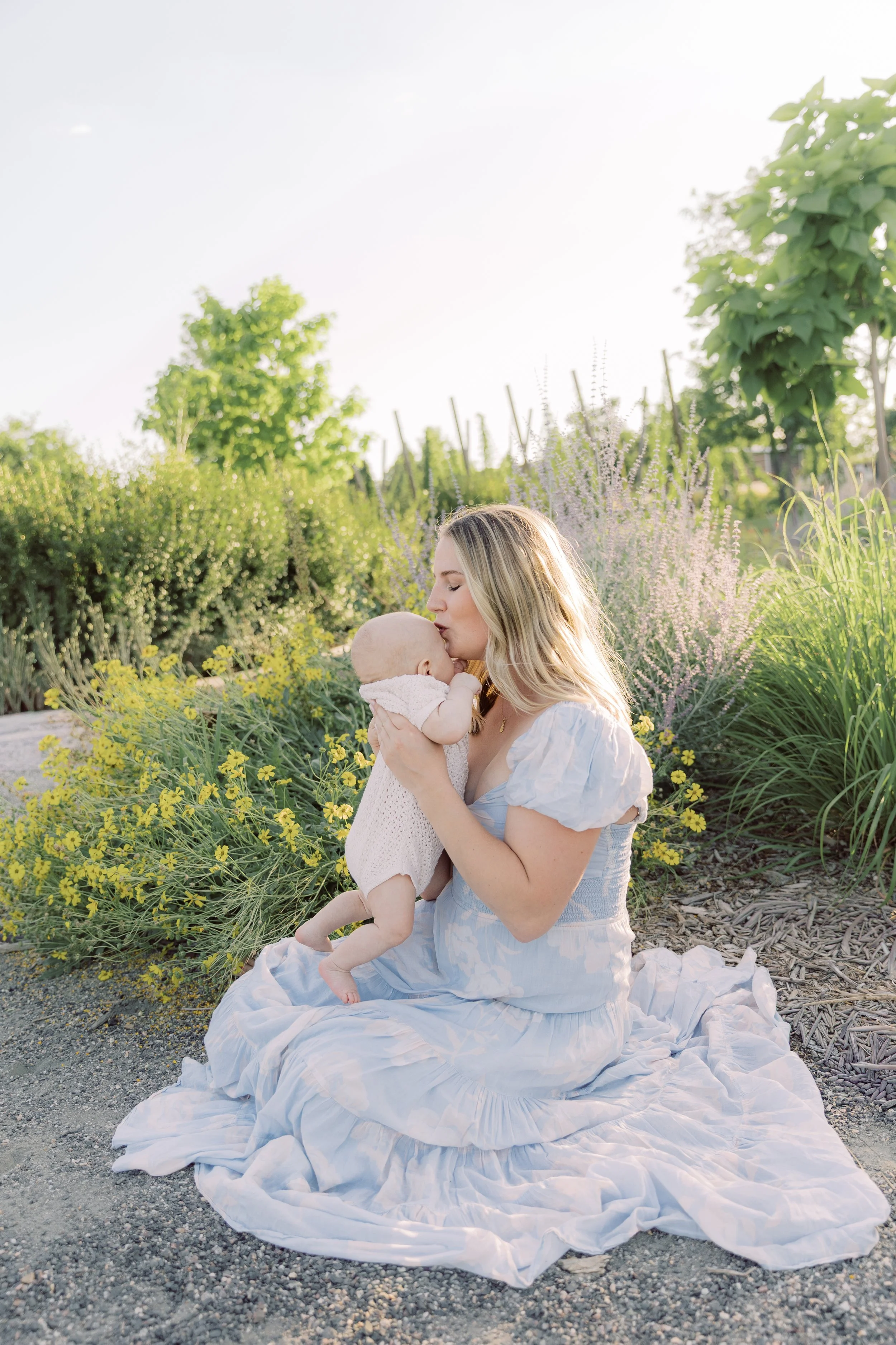 Mom kissing baby boy in floral garden during a Fort Collins family photography session.