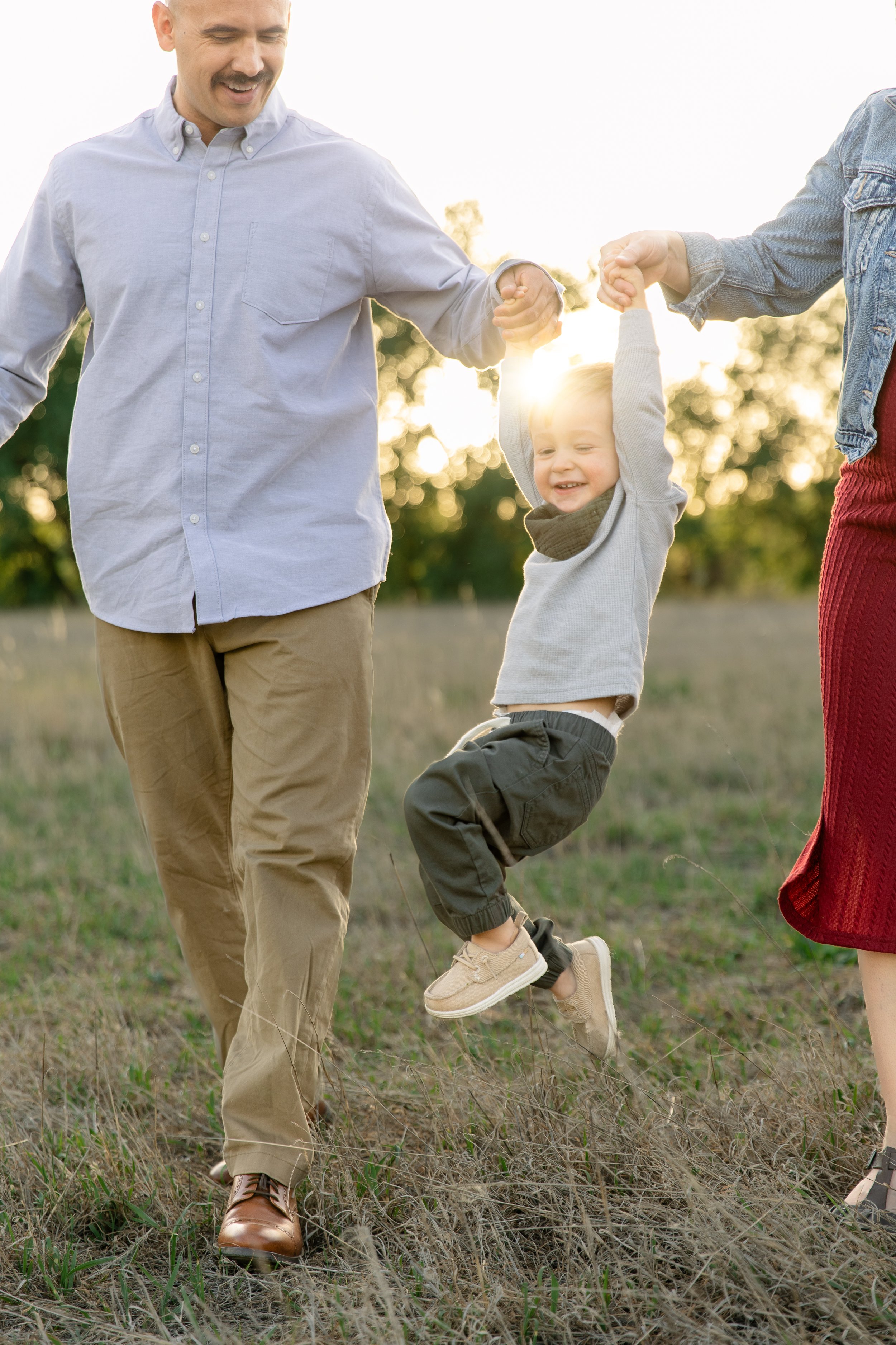 Parents swinging toddler during a spring photo session in Windsor, Colorado