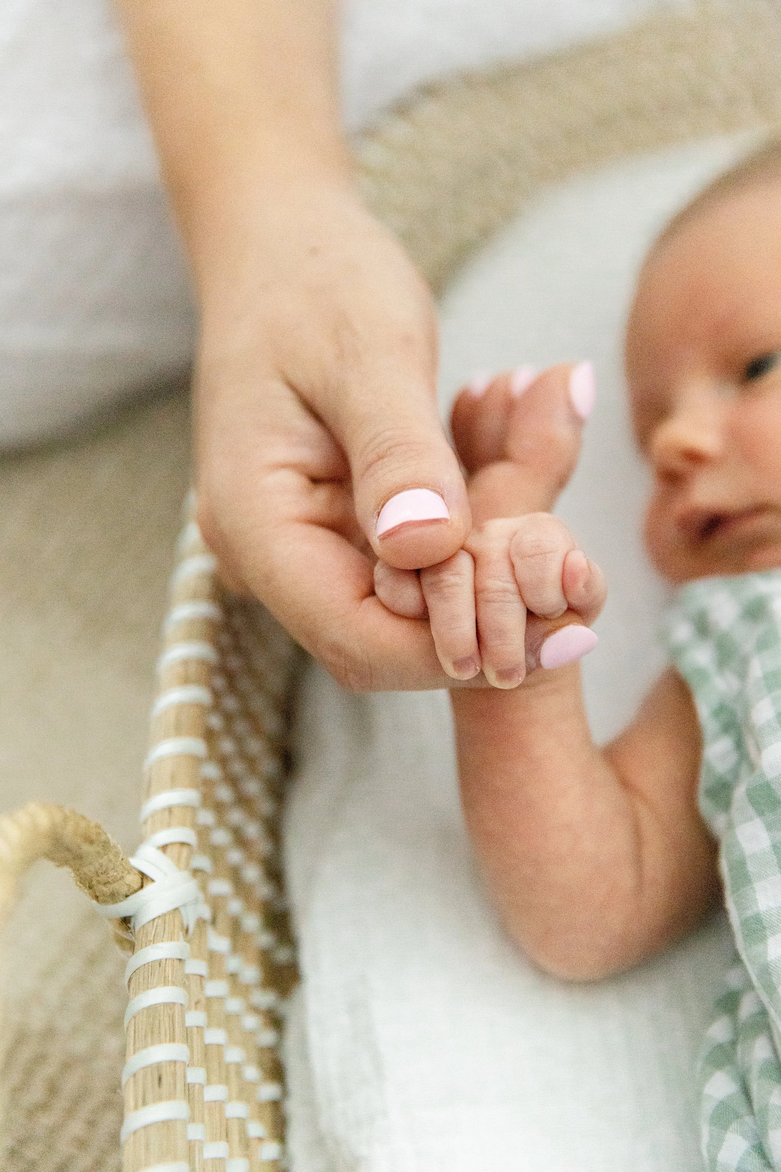 Mother holds baby's hand during an in-home newborn photography session near Fort Collins, Colorado.