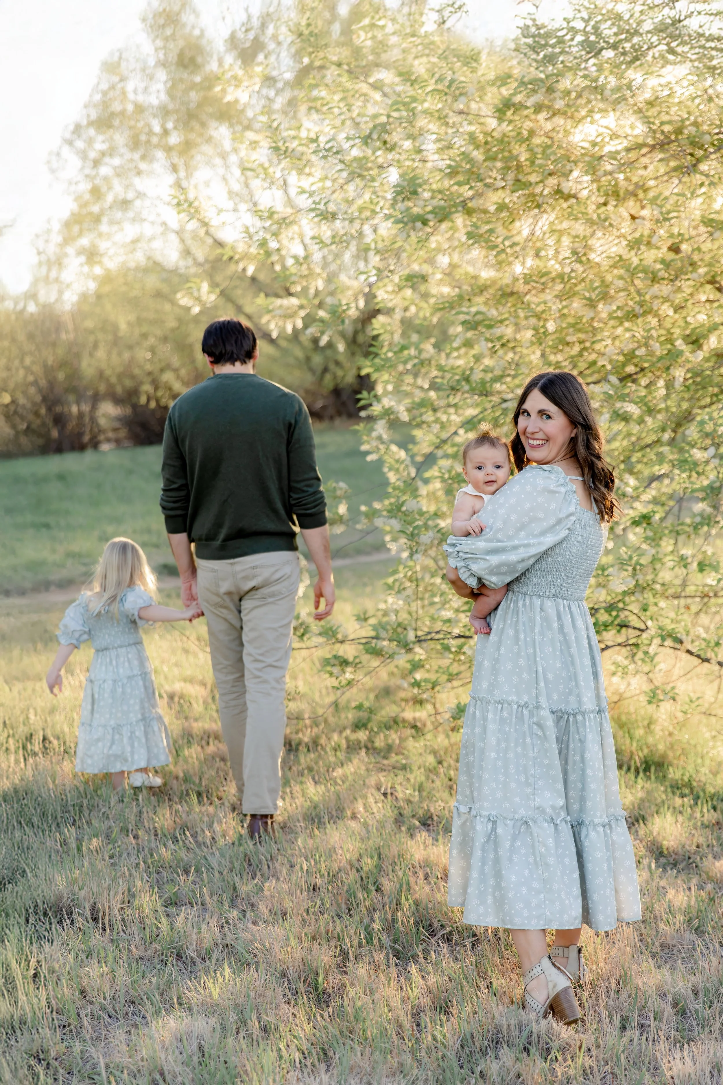 Mom holding baby boy near flowering tree during Fort Collins family photography session.