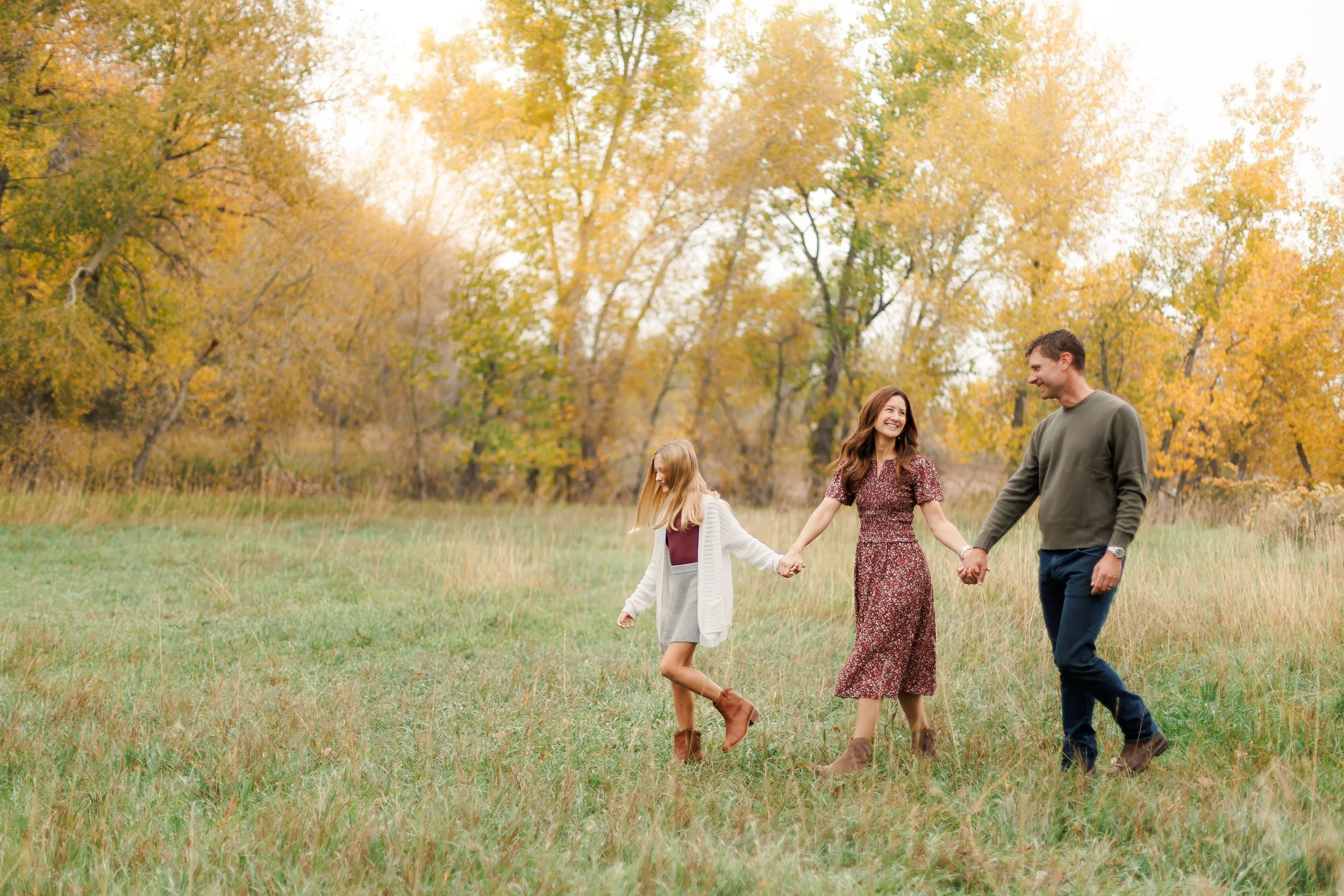 A family enjoys a walk during a fall mini photography session in Fort Collins, Colorado
