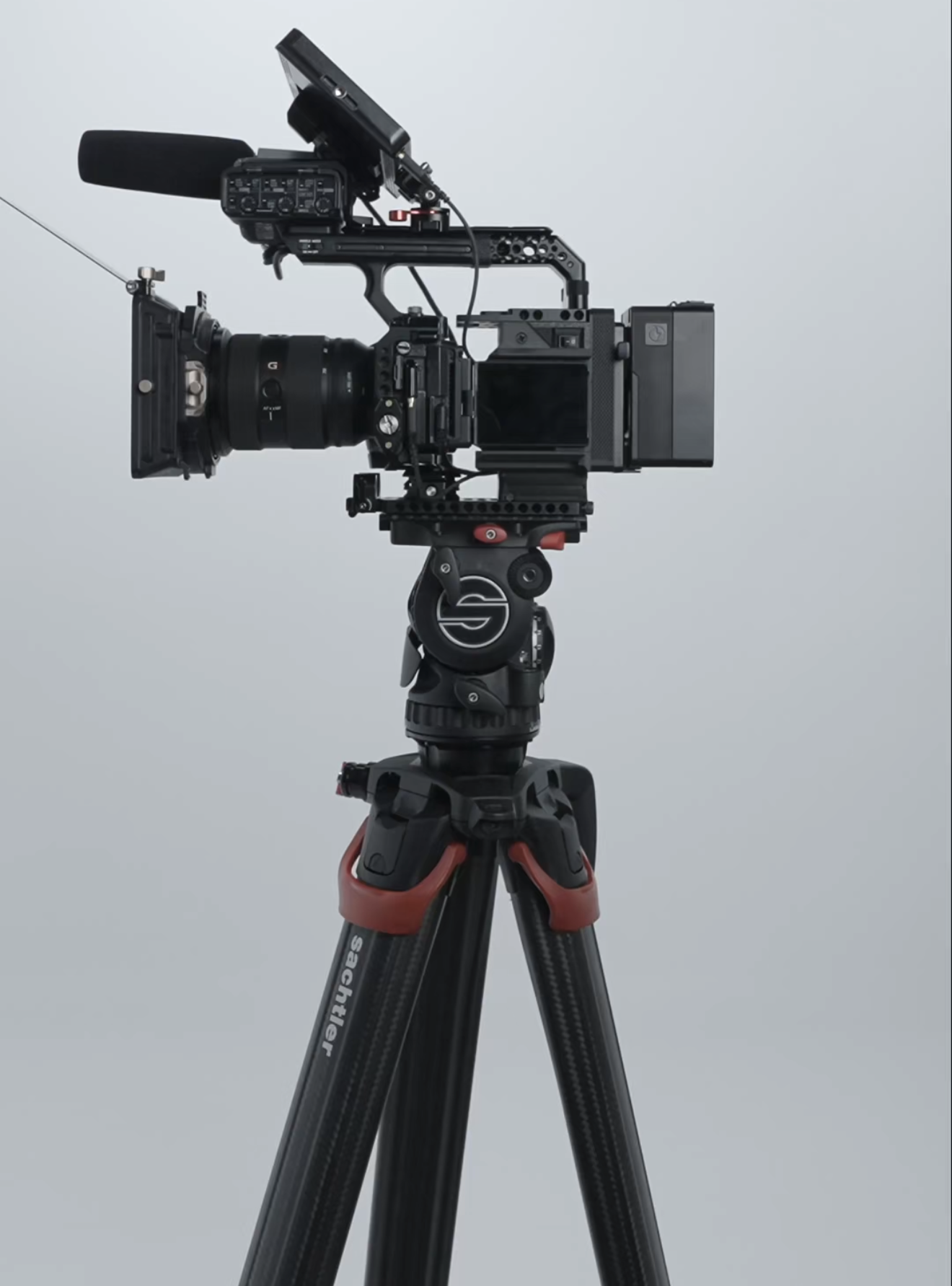 A professional film camera mounted on a tripod with a gray background.