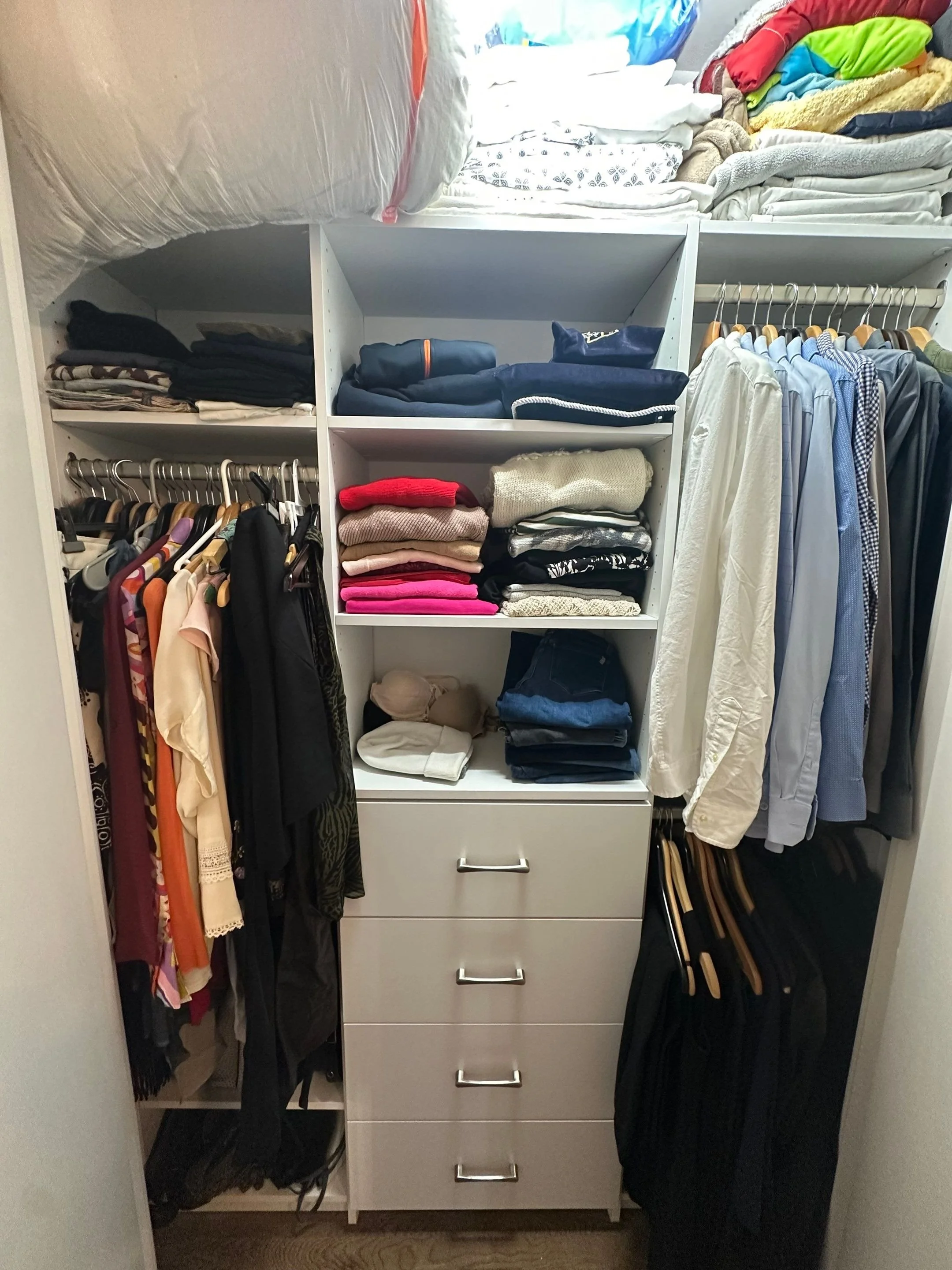 A closet with clothing and linens organized on shelves, hanging racks, and drawers.