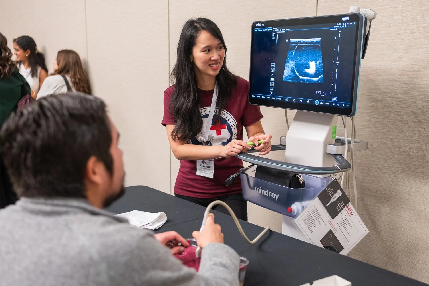 Young Doctor stands beside an ultrasound machine helping teach a medical student - medical conference photography