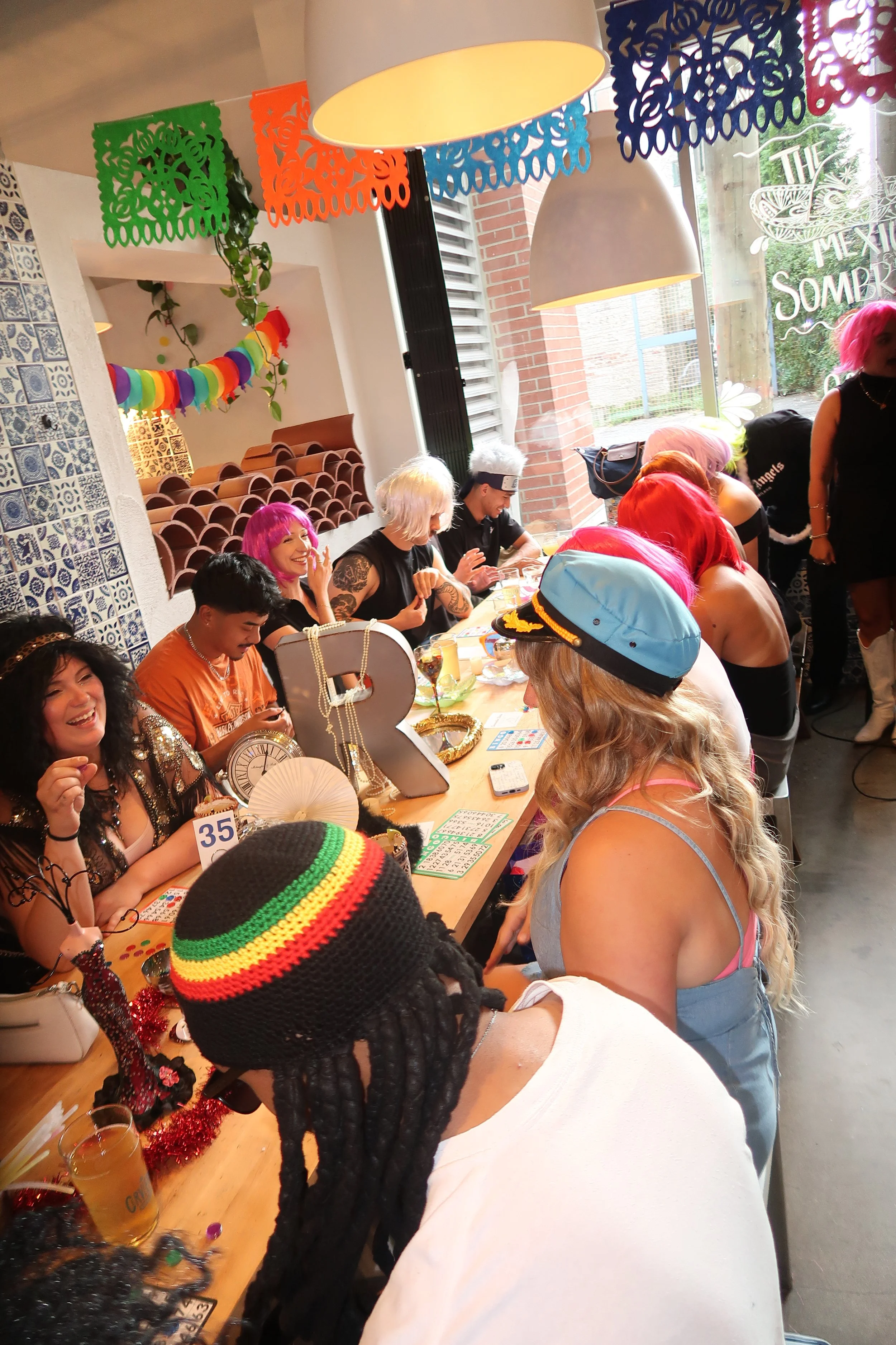People gathered around a decorated table celebrating a birthday party with colorful decorations and attire.