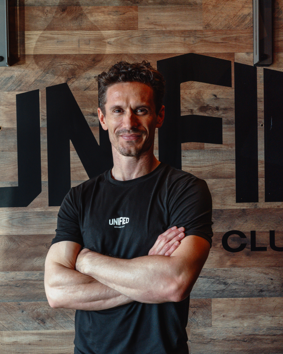 A young man practicing boxing with a punching bag in a gym.