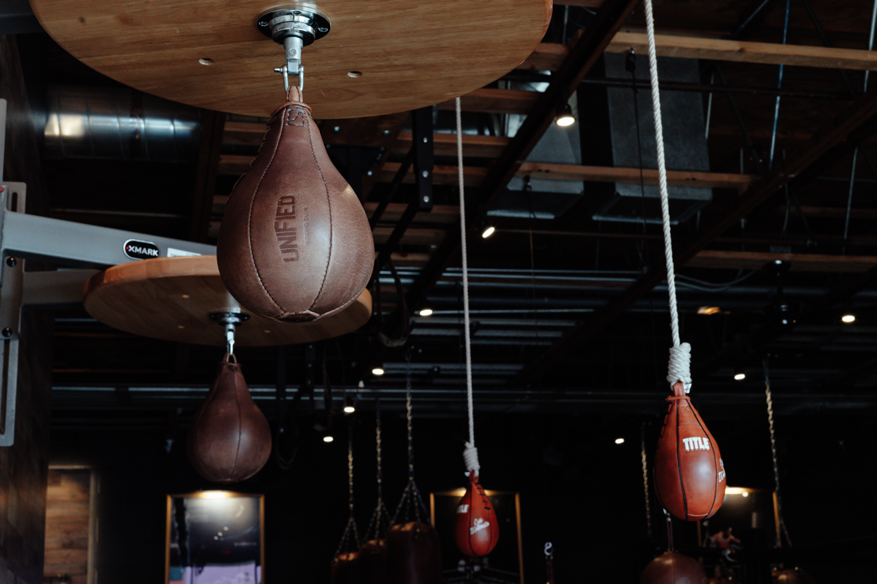 Multiple punching bags hanging from the ceiling of a gym or boxing studio.