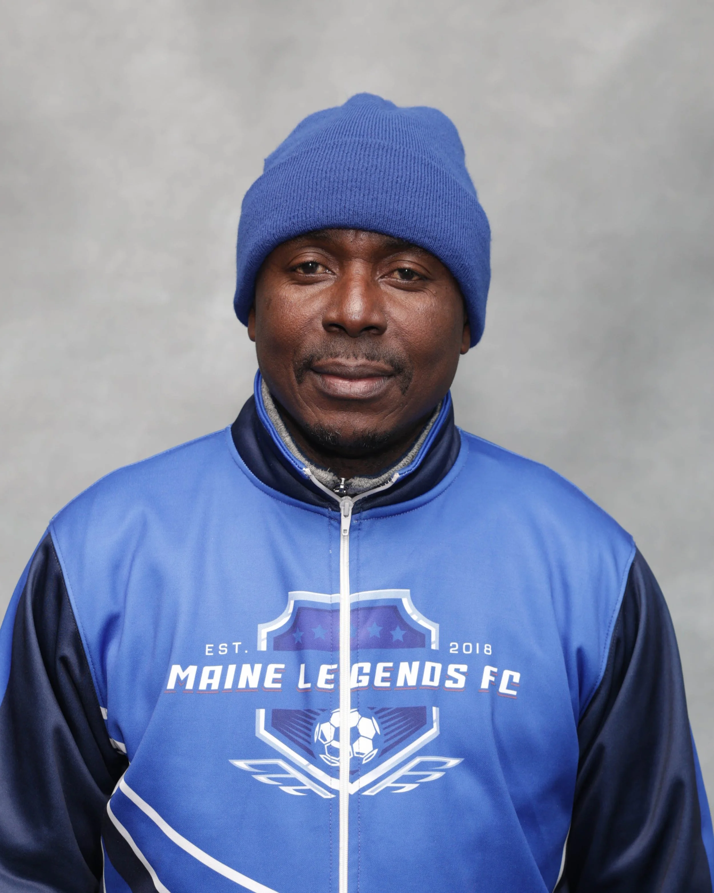 Logo for Maine Legends FC, established in 2018, featuring a shield with a soccer ball at the bottom and five stars at the top, in blue and white colors.