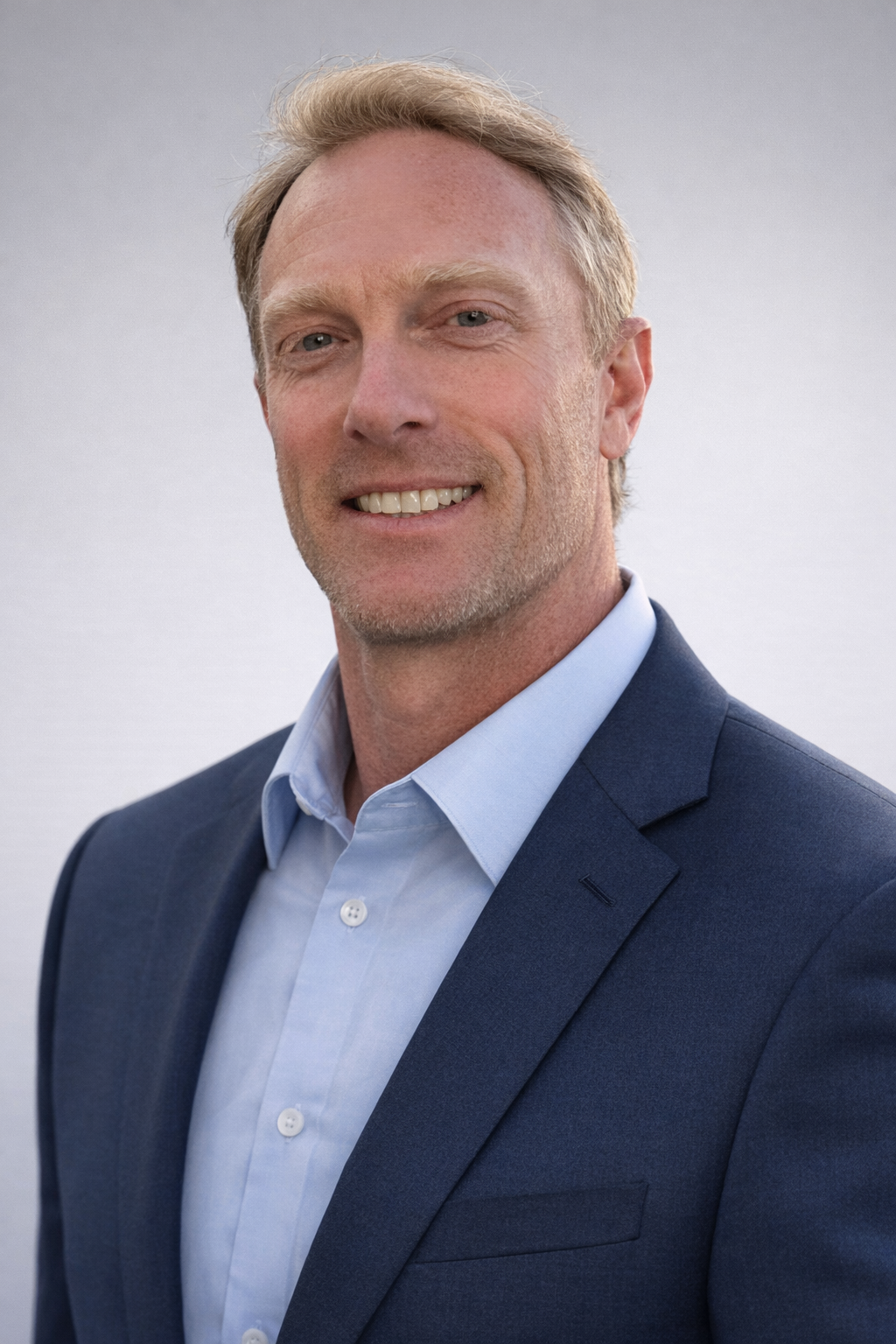 Smiling man in white shirt in front of brick wall