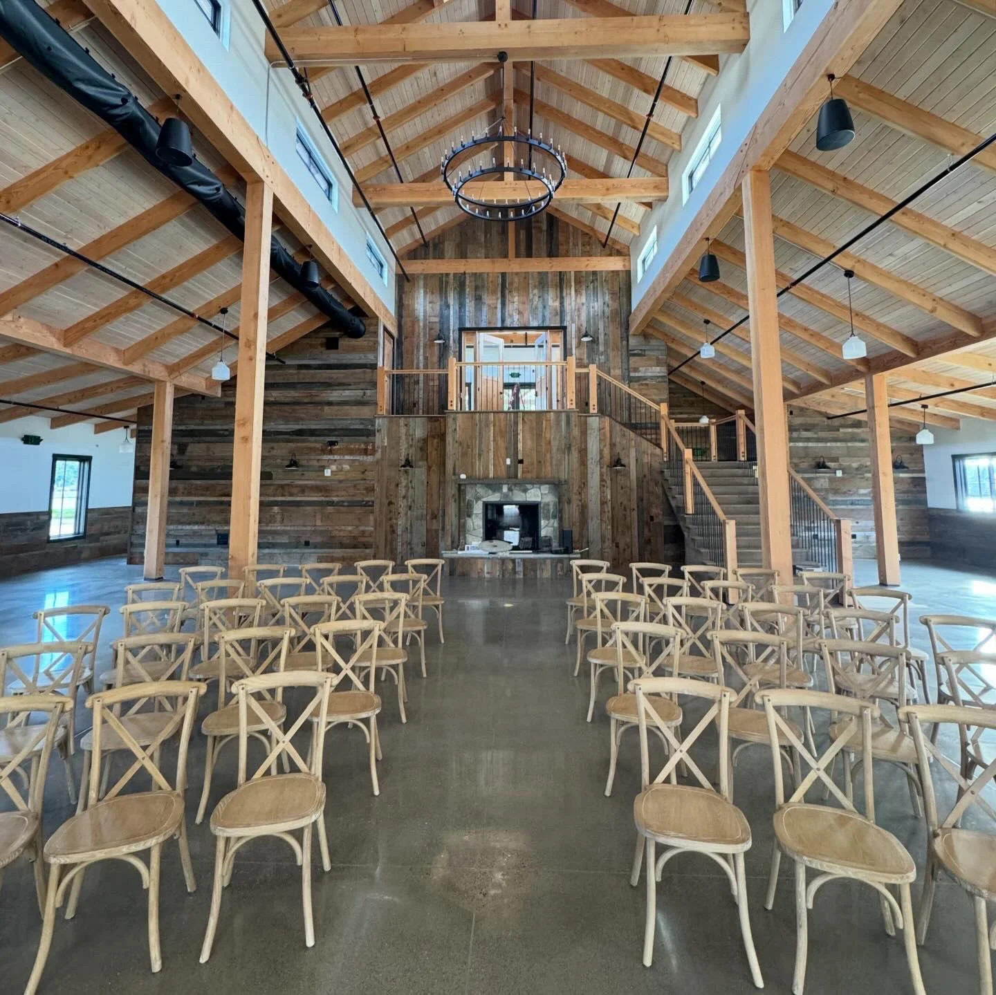 Construction site of a building interior with wooden beams, large windows, and construction equipment scattered on the unfinished floor.