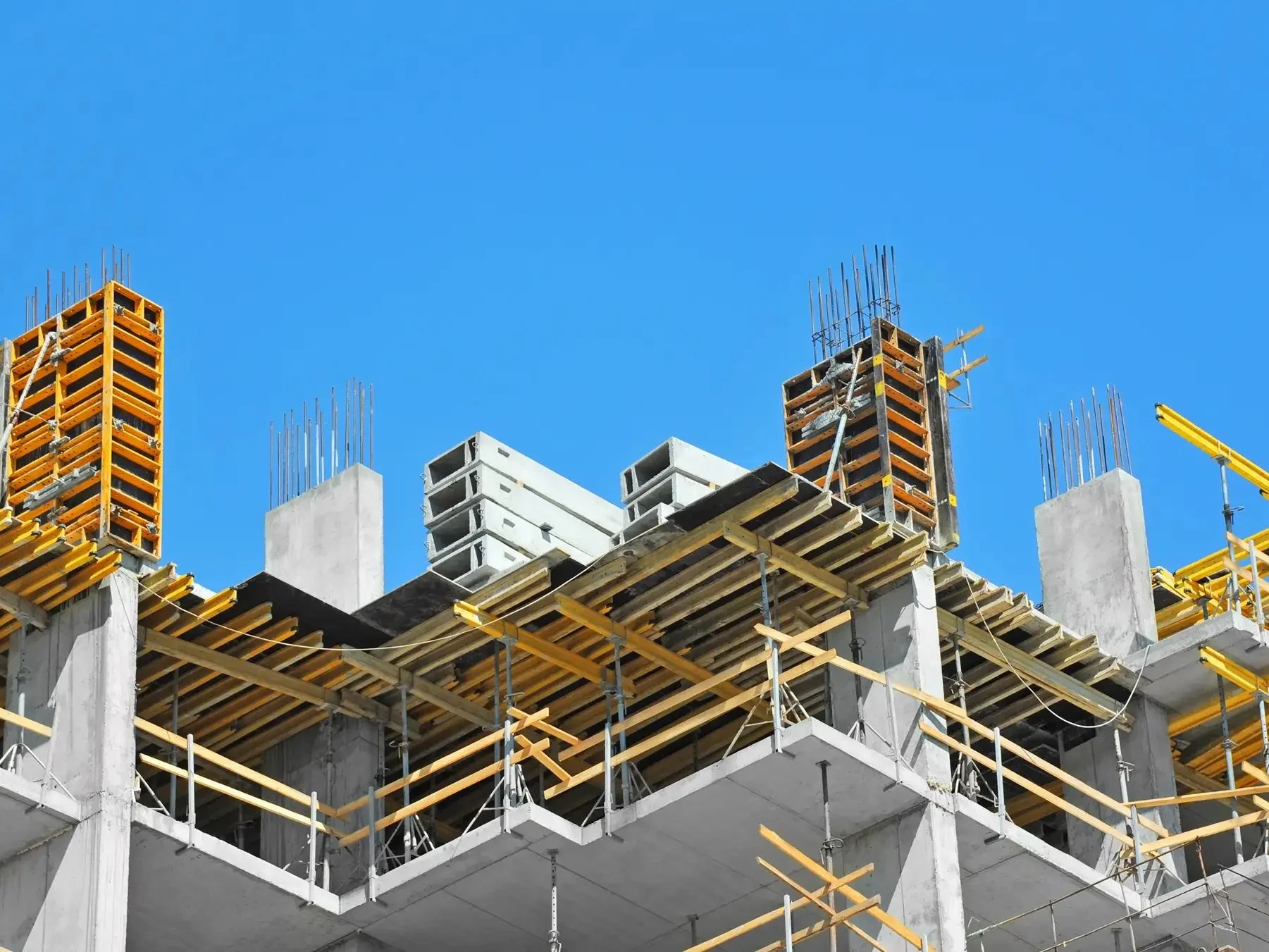Concrete building under construction with scaffolding and blue sky background.