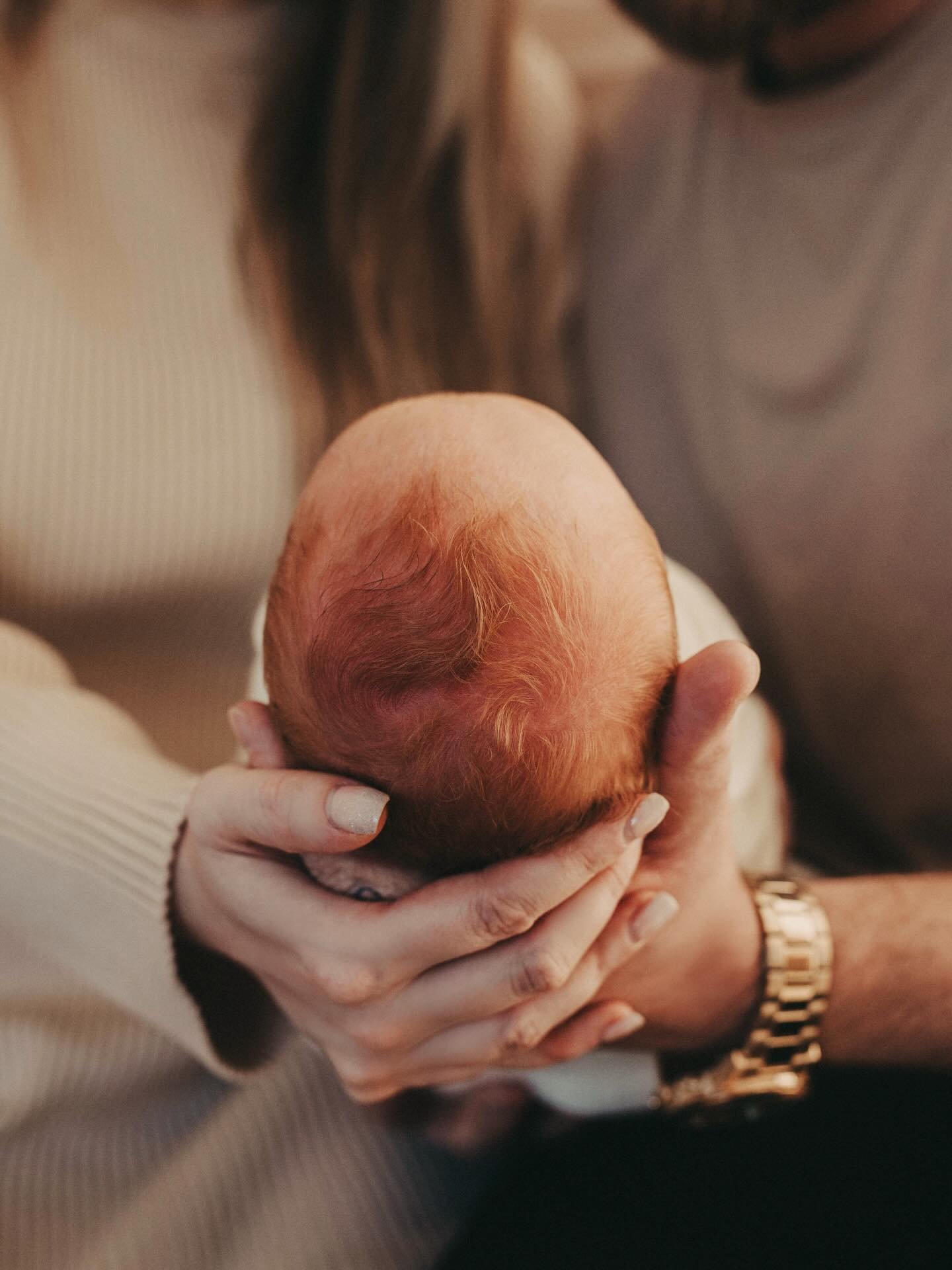 Wrapped in two pairs of hands, the world pauses.
A brand-new head, still warm with beginnings, rests where love already knows what to do. The room is quiet except for breathing&mdash;one life just arrived, two lives forever changed. In this small mom