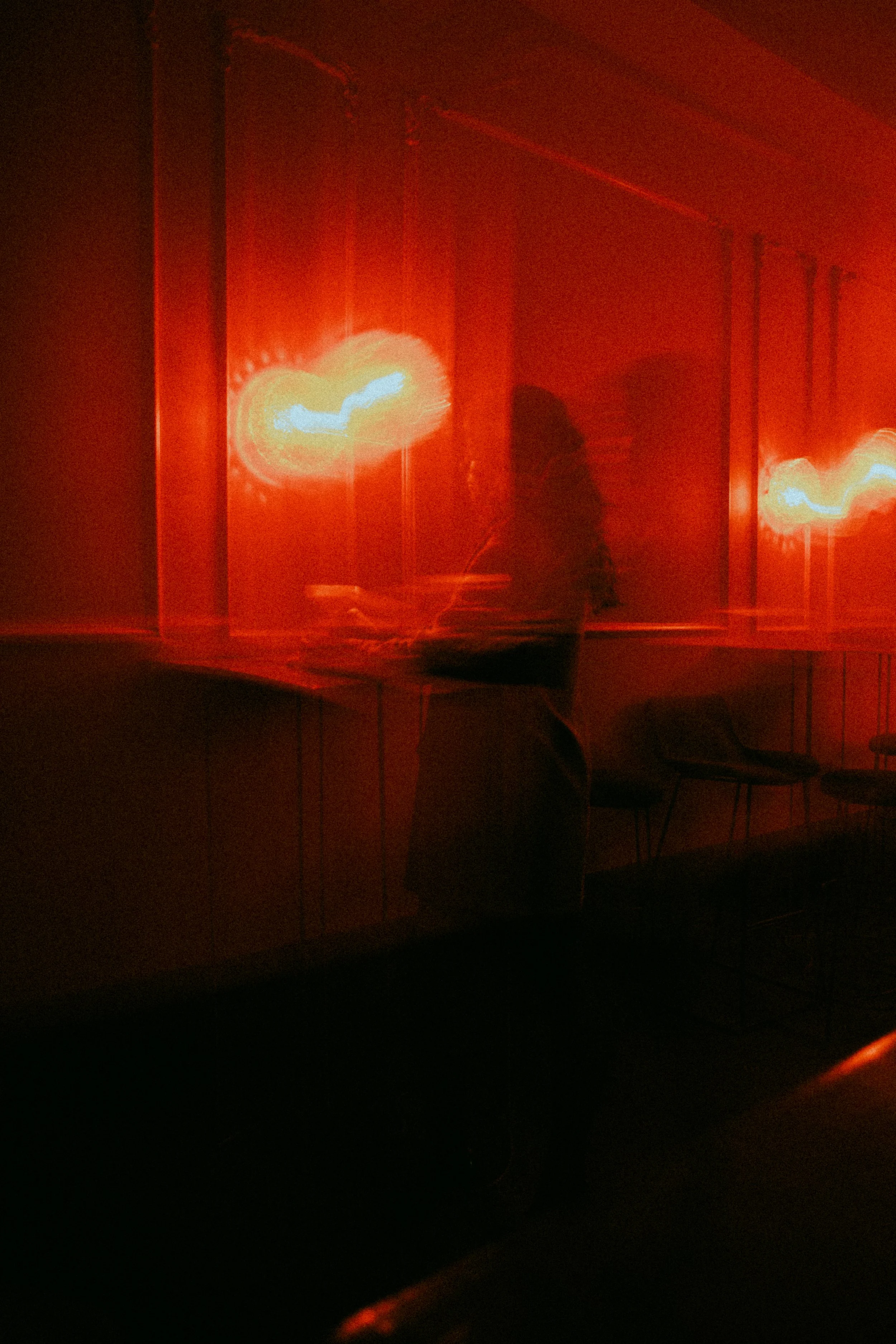 A person standing near a wall with three illuminated red lights, giving a blurry and abstract appearance.