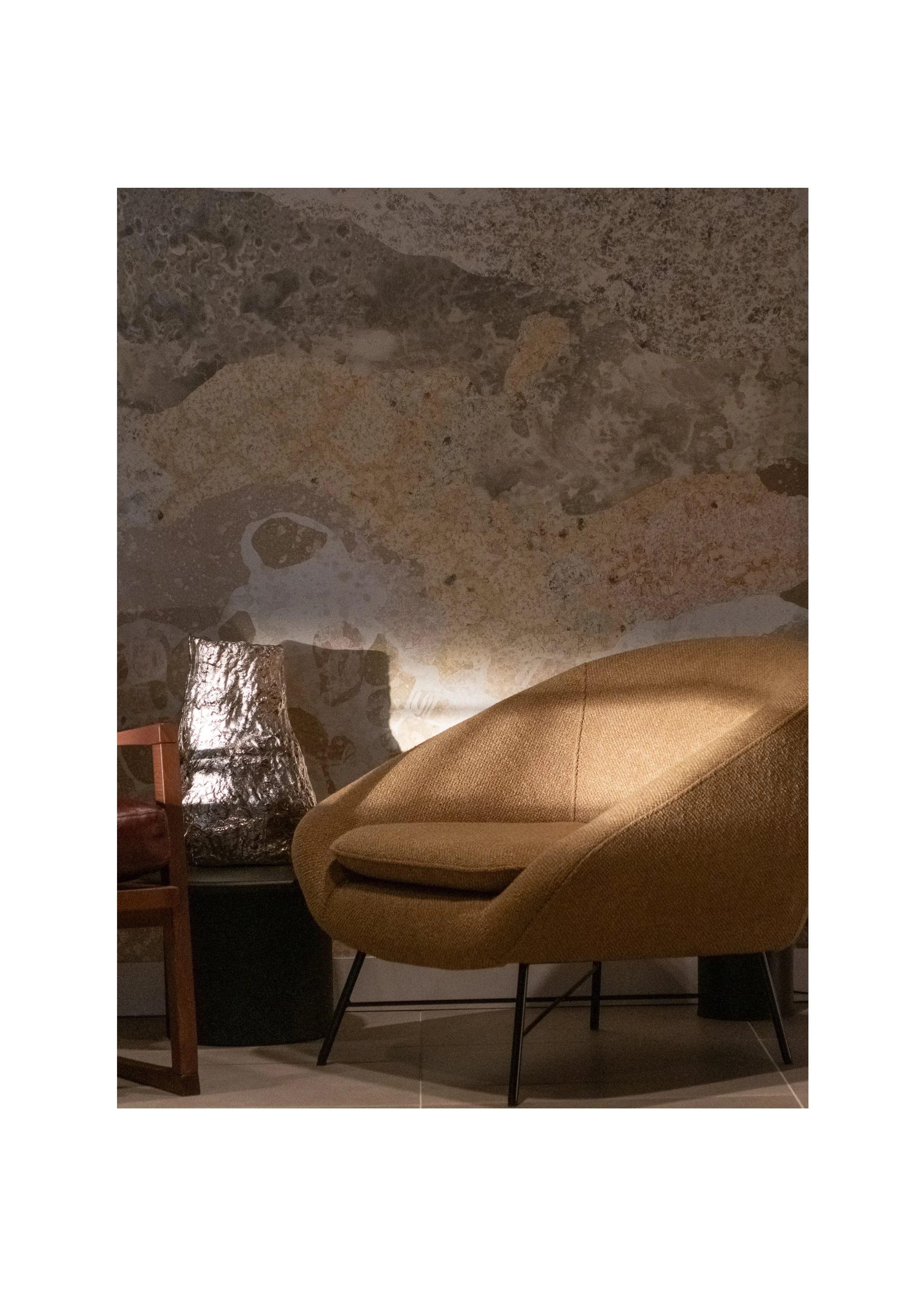 Designer armchair and textured wall feature under dramatic shadow and light, architectural interior photography.