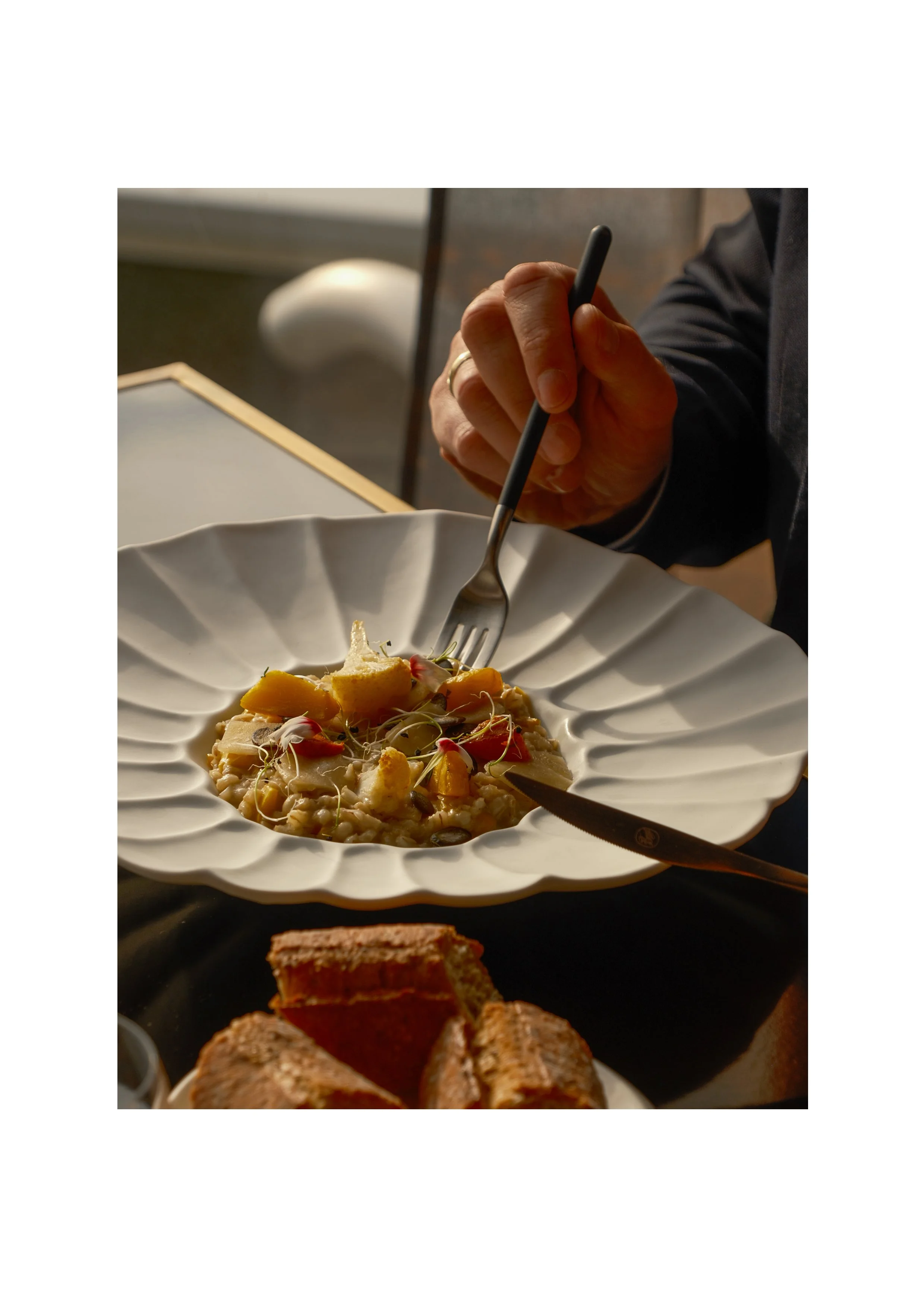 Close-up of a seasonal risotto dish with human interaction, showcasing the hotel's dining atmosphere.