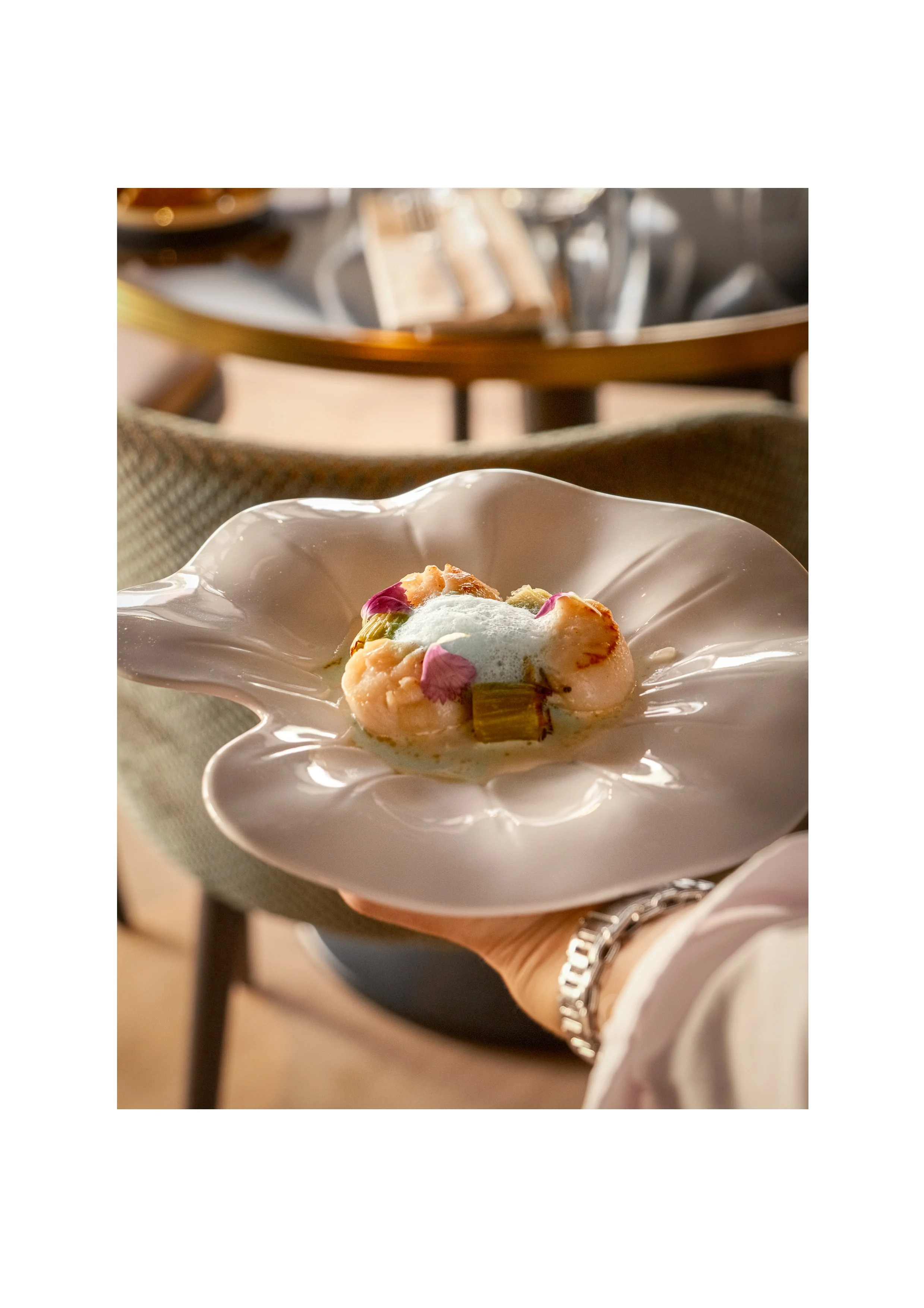 Seared scallop presentation on a floral-shaped designer plate, luxury hospitality photography.