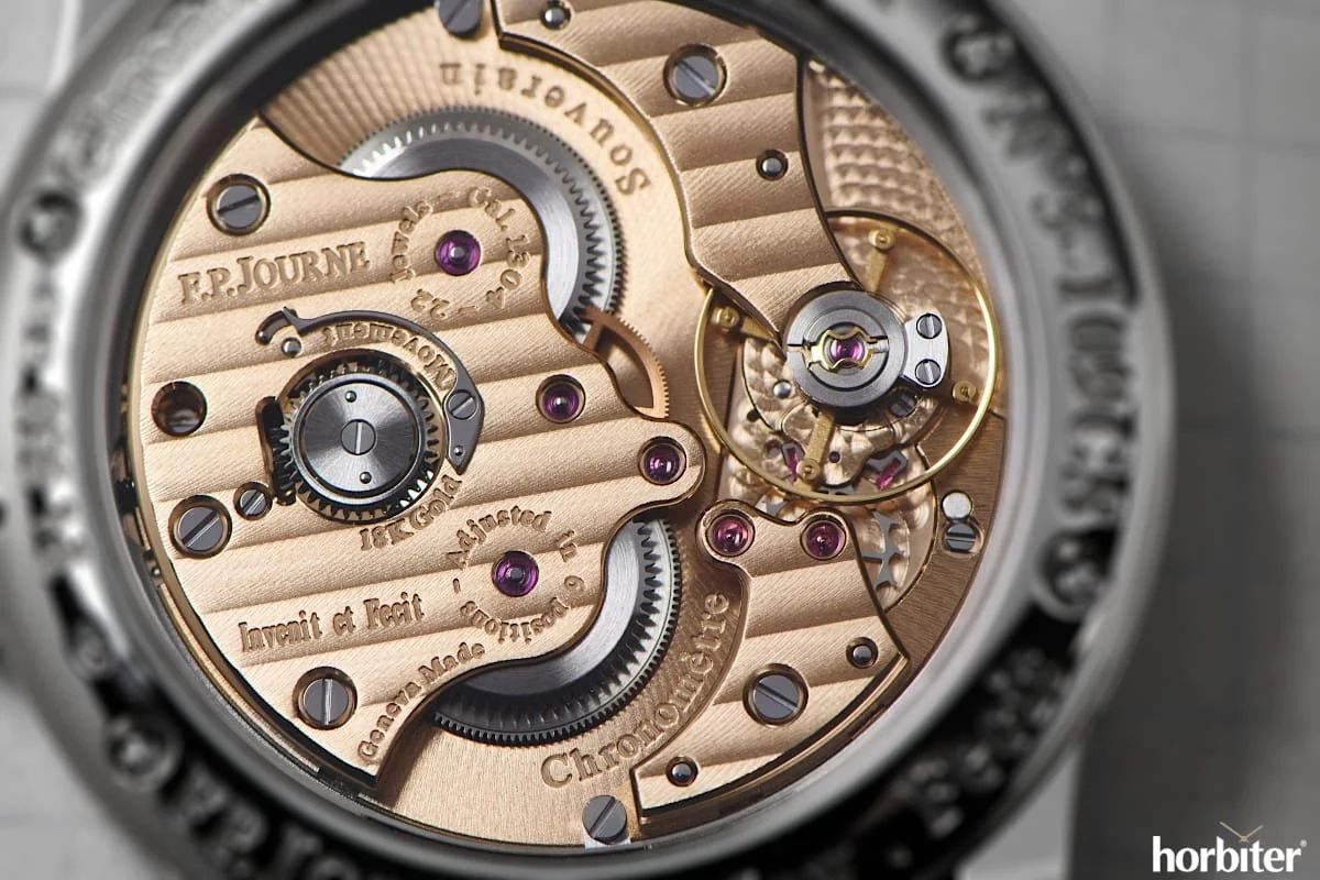 Mécanisme de montre de luxe avec engrenages en or et composants en acier visible, gravure sur la surface, et petites pierres précieuses enroulées dans le mouvement.