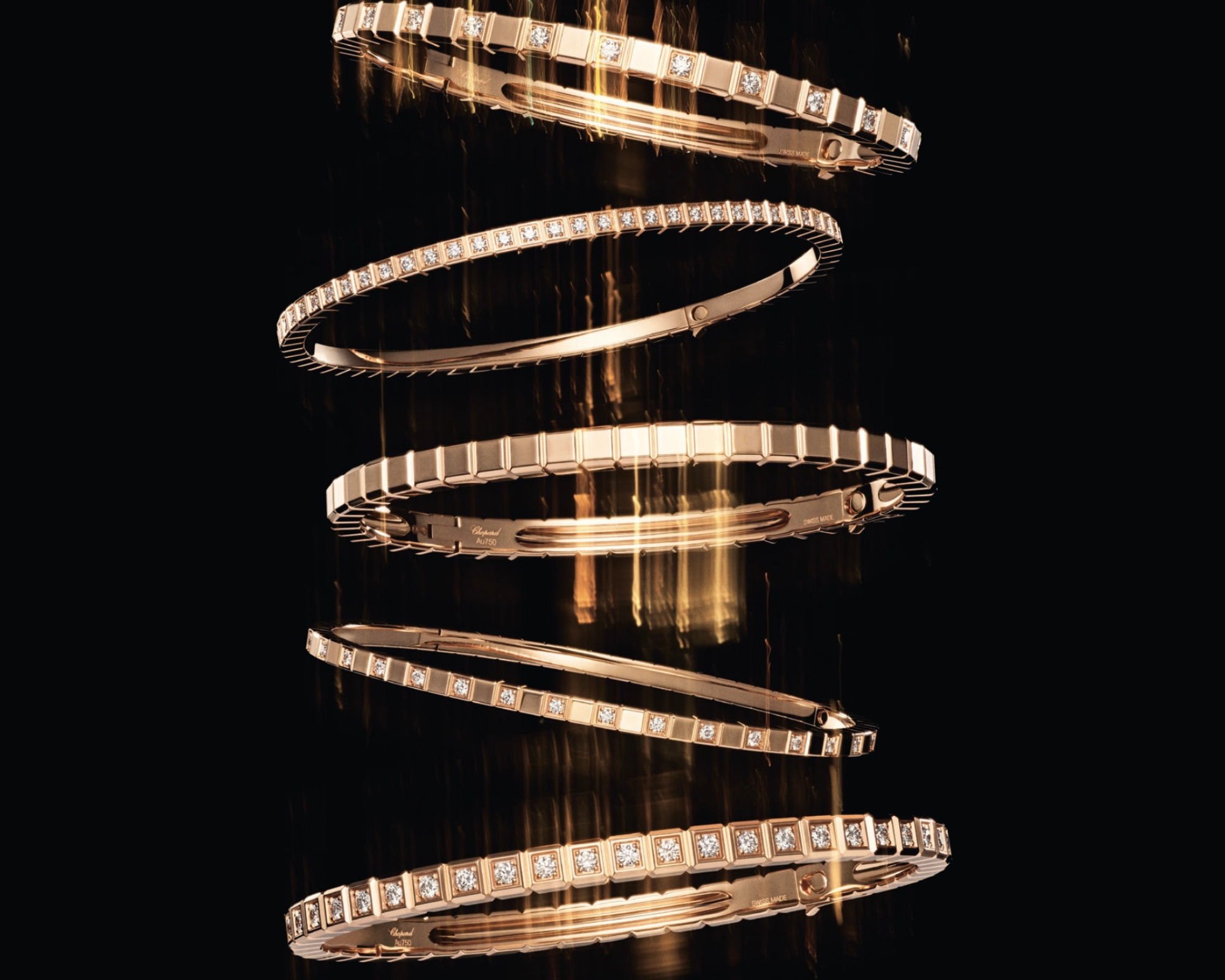 Bracelets en or rose avec des diamants suspendus contre un fond noir.