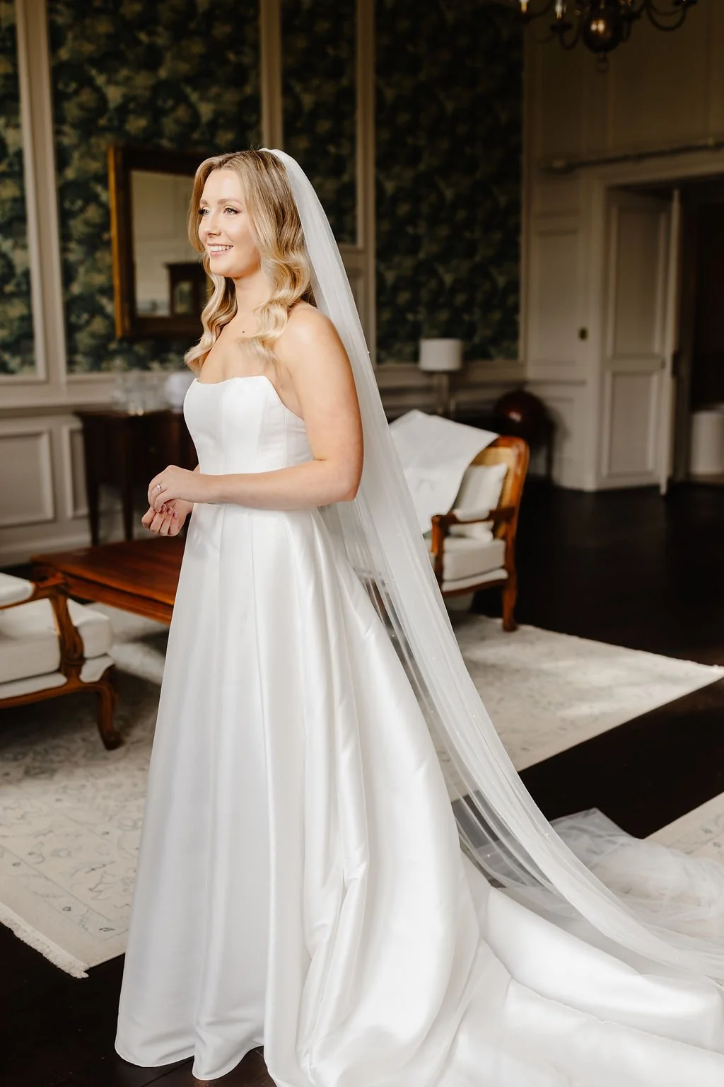Bride in a white wedding gown with long veil in a elegantly decorated room.
