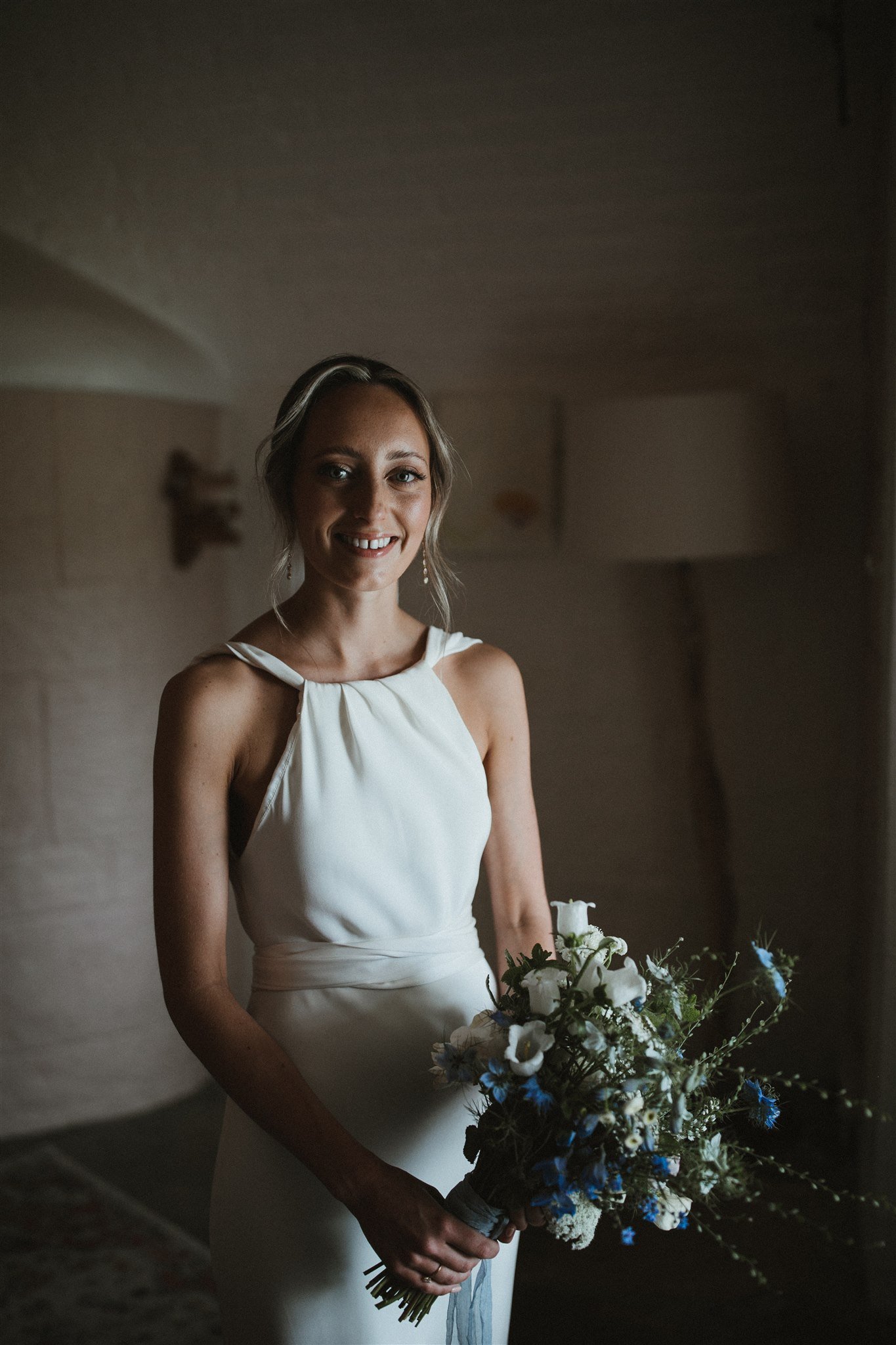 Bride in white dress holding bouquet indoors