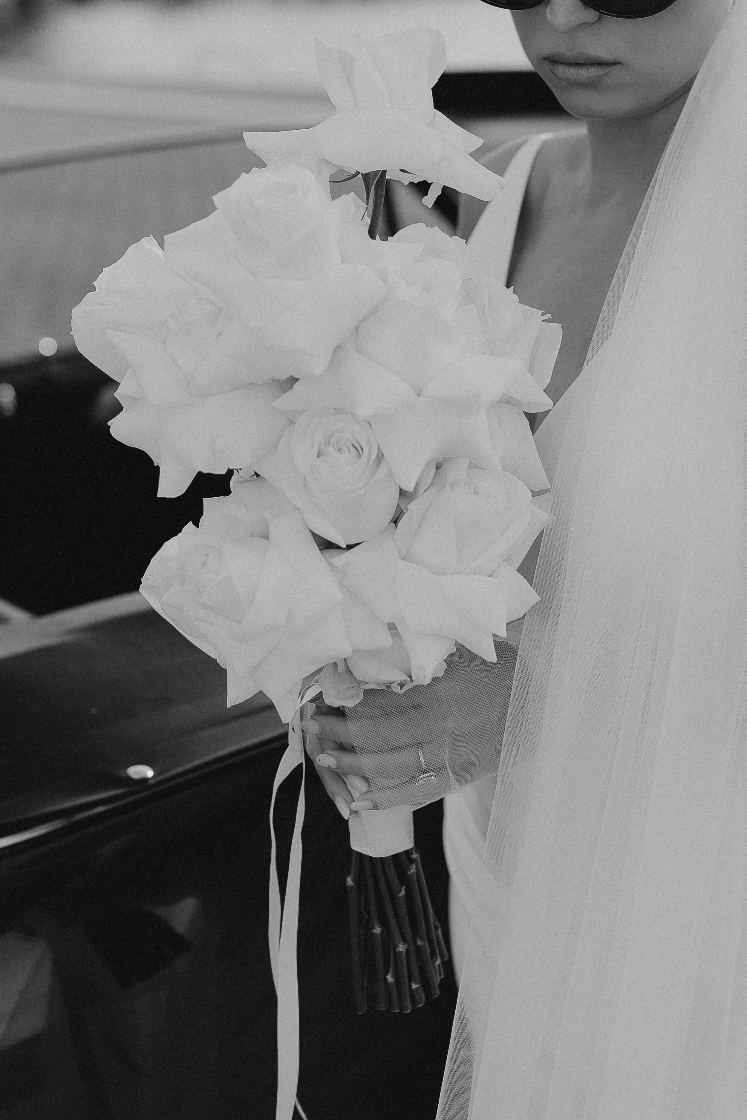 Eine Frau in Brautkleid hält einen Brautstrauß mit Rosen und anderen Blumen.