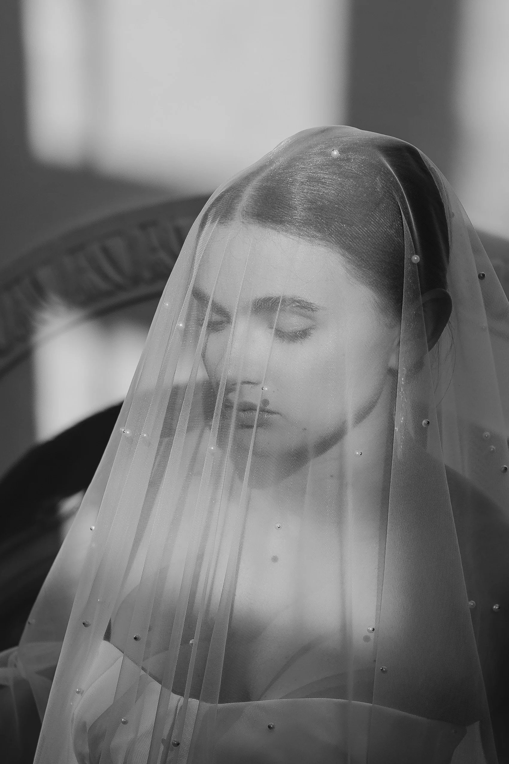 Schwarz-weiß-Foto einer jungen Frau mit Tuch über dem Kopf, die nach unten schaut.