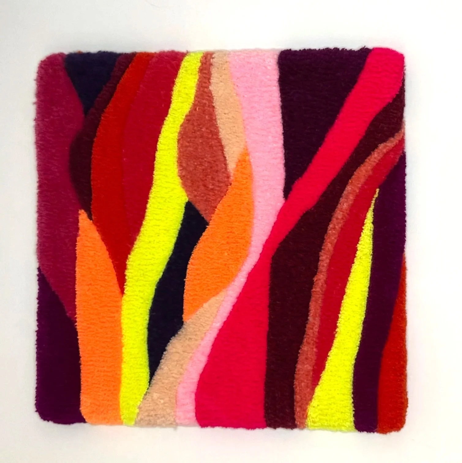 Colorful abstract woven textile with wavy stripes of red, pink, orange, yellow, brown, and black.