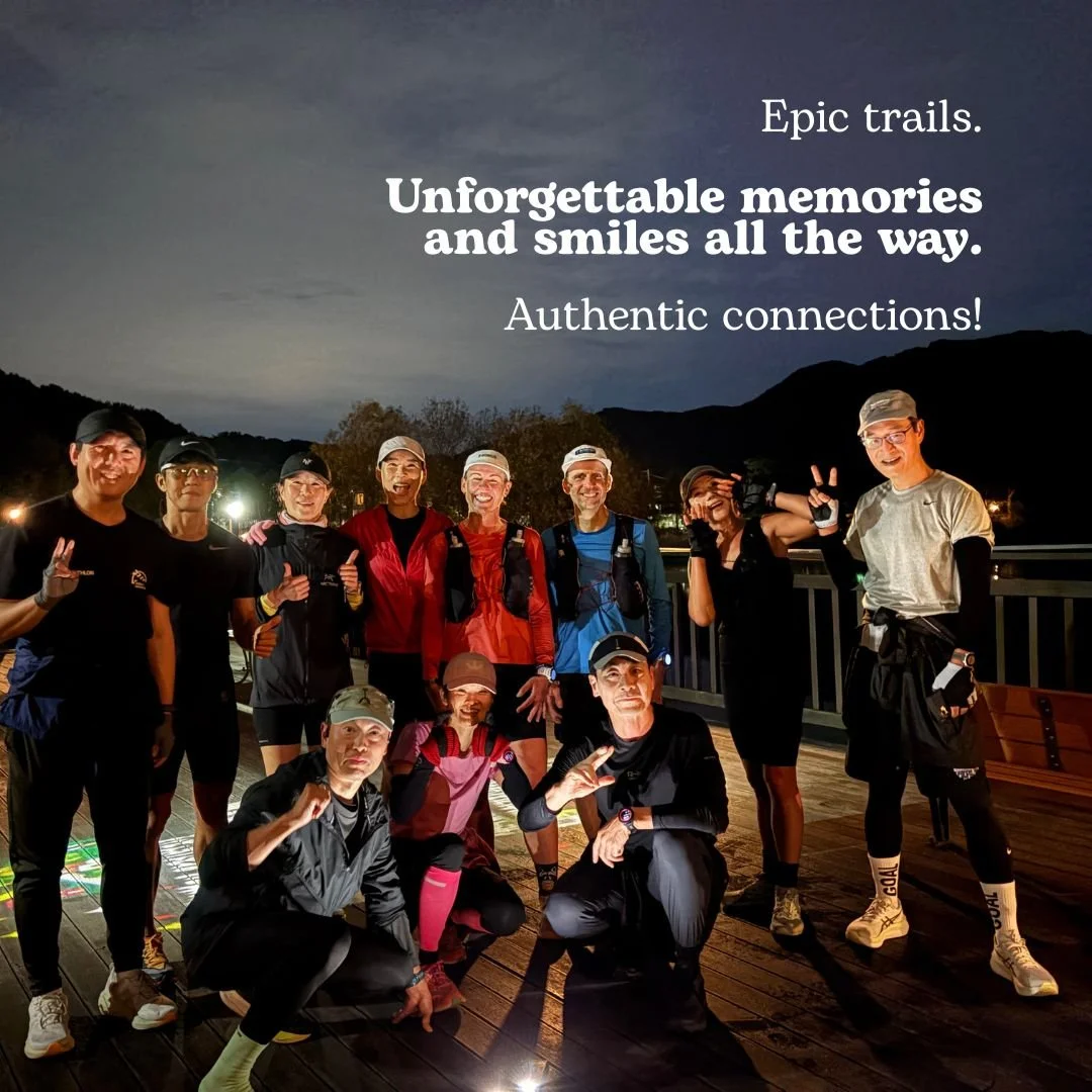 Group of trail runners smiling and posing together on a boardwalk at night.