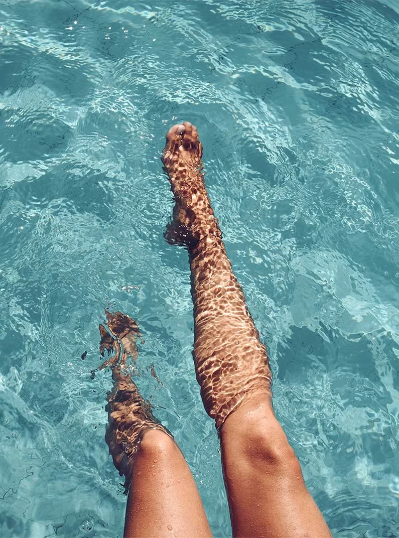 Baigneuse les jambes dans l'eau claire d'une piscine, vue du dessus