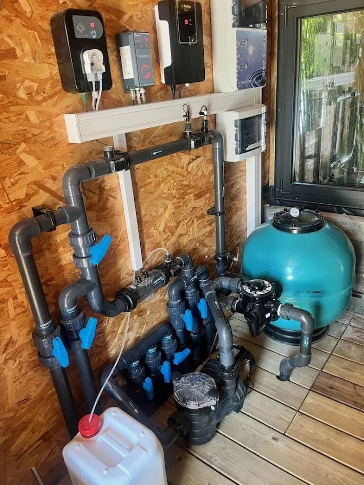 Local technique de piscine avec filtre à sable, pompe et vannes de filtration
